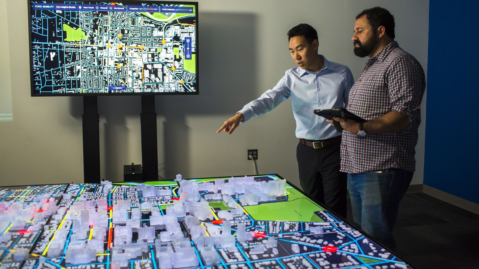 A man points to a physical blueprint of a city.