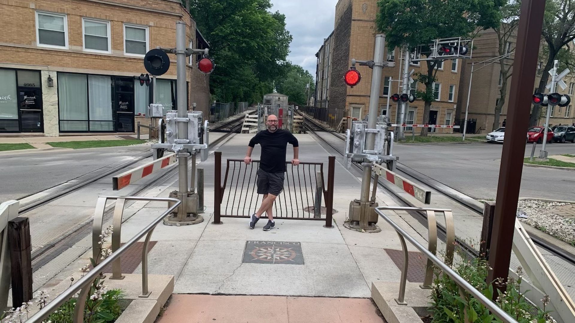Photo of a man standing in the middle of train crossing tracks