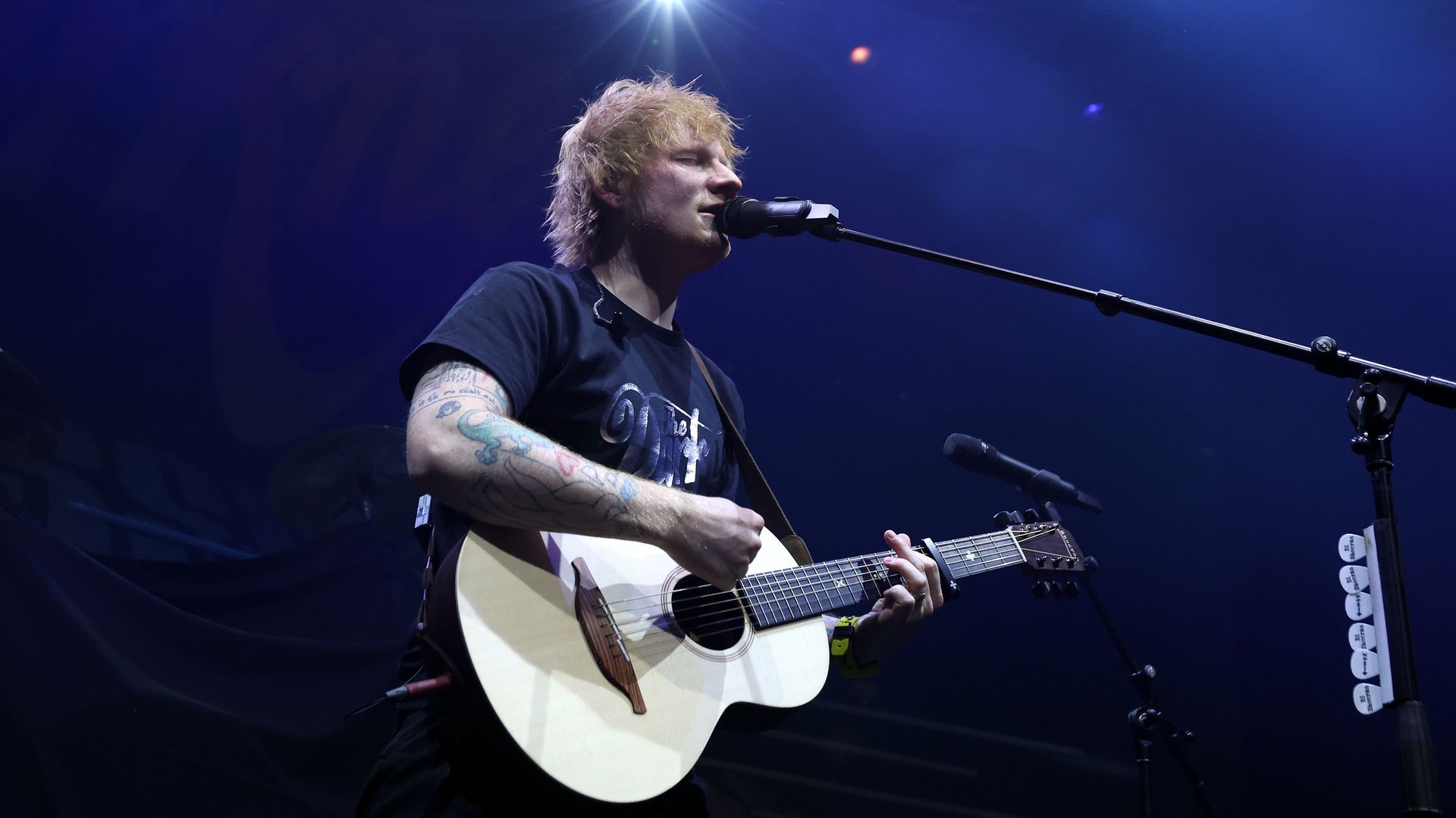 Ed Sheeran sings while playing an acoustic guitar on stage in London in December 2023.
