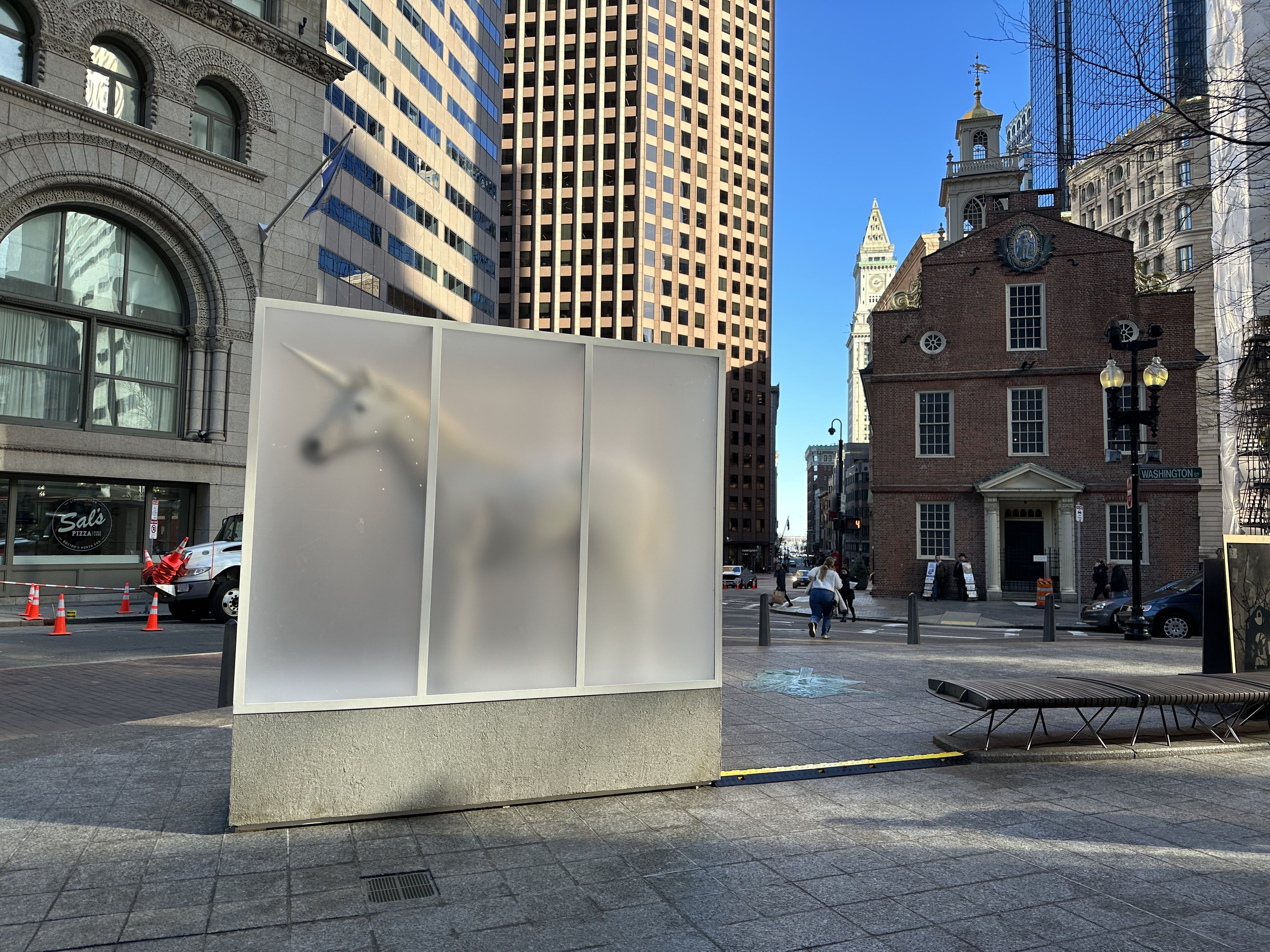 A sculpture of a unicorn sits inside a frosted glass case outside the old State House.