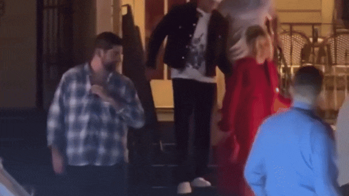 Two people quickly leave a restaurant and head to a waiting car. 