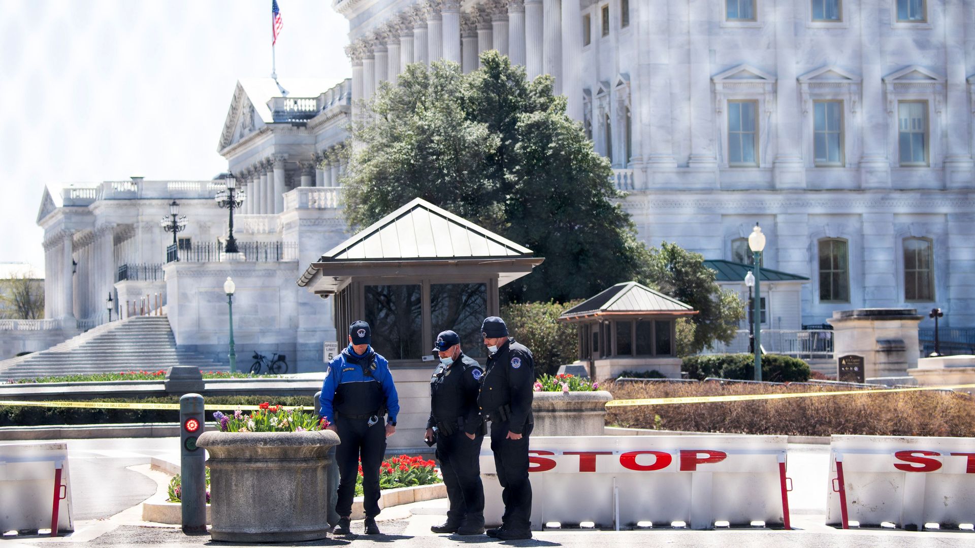 Three Capitol police officers stand in front of the complex, with the U.S. flag at half-mast in the background