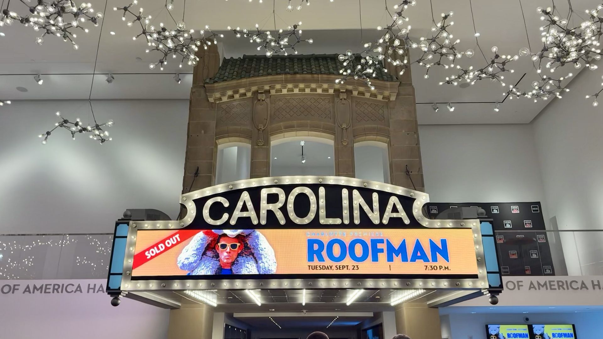 Marquee with lights spelling "CAROLINA" above a digital screen advertising "ROOFMAN" event on Tuesday, Sept. 23, 7:30 p.m., marked sold out, with decorative branch-like ceiling lights.