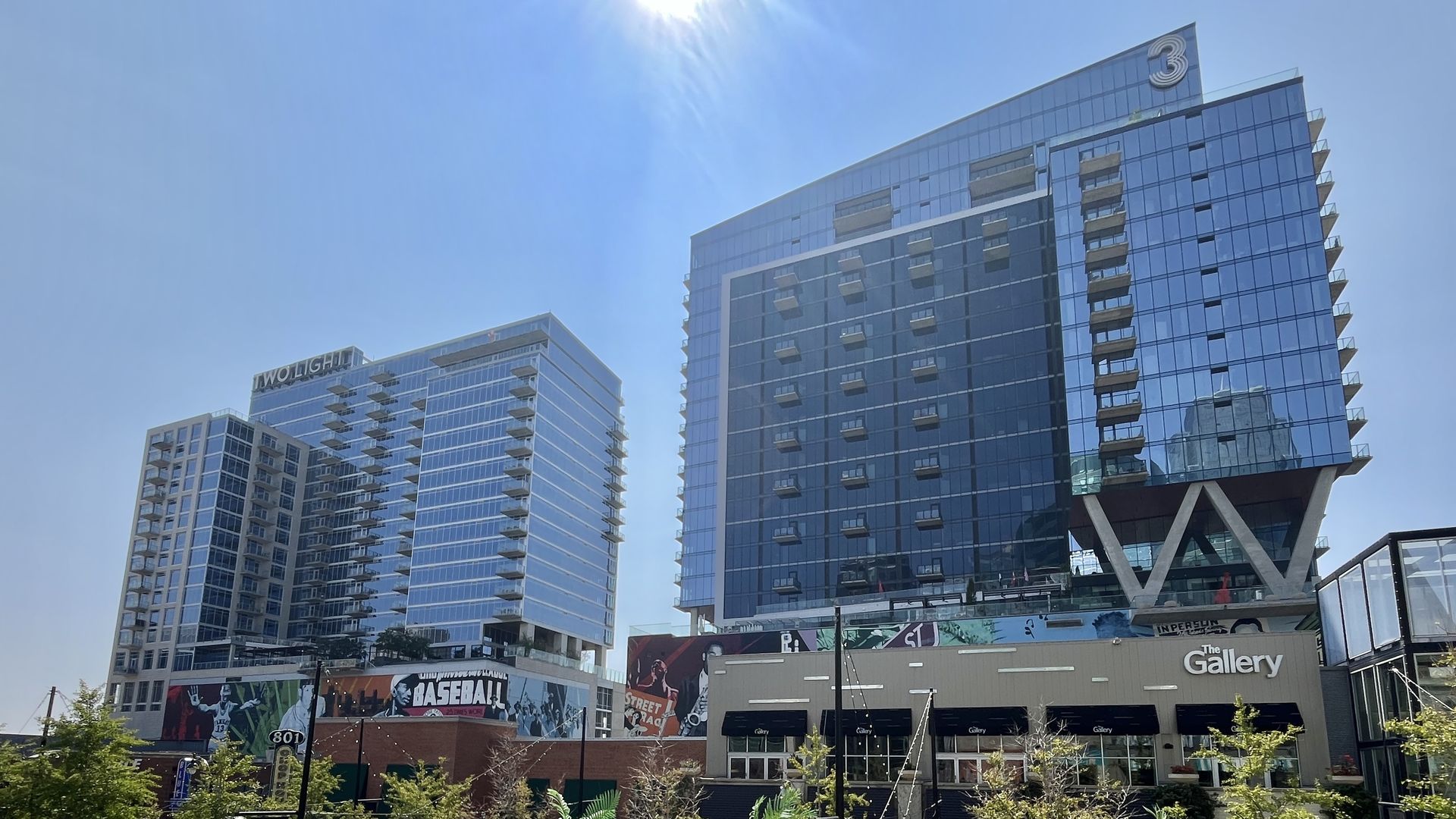 Two modern glass buildings under a bright blue sky in downtown Kansas City, one labeled "TWO LIGHT" and the other "3" with balconies on a sunny day.