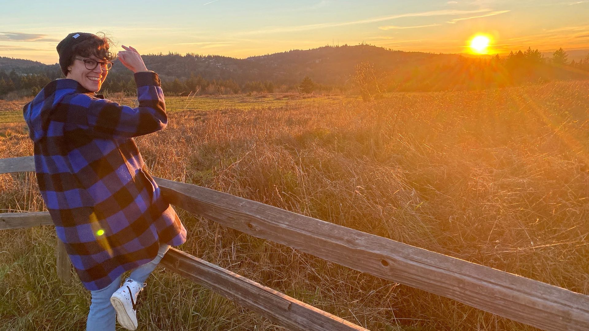 A person standing and facing a sunset.