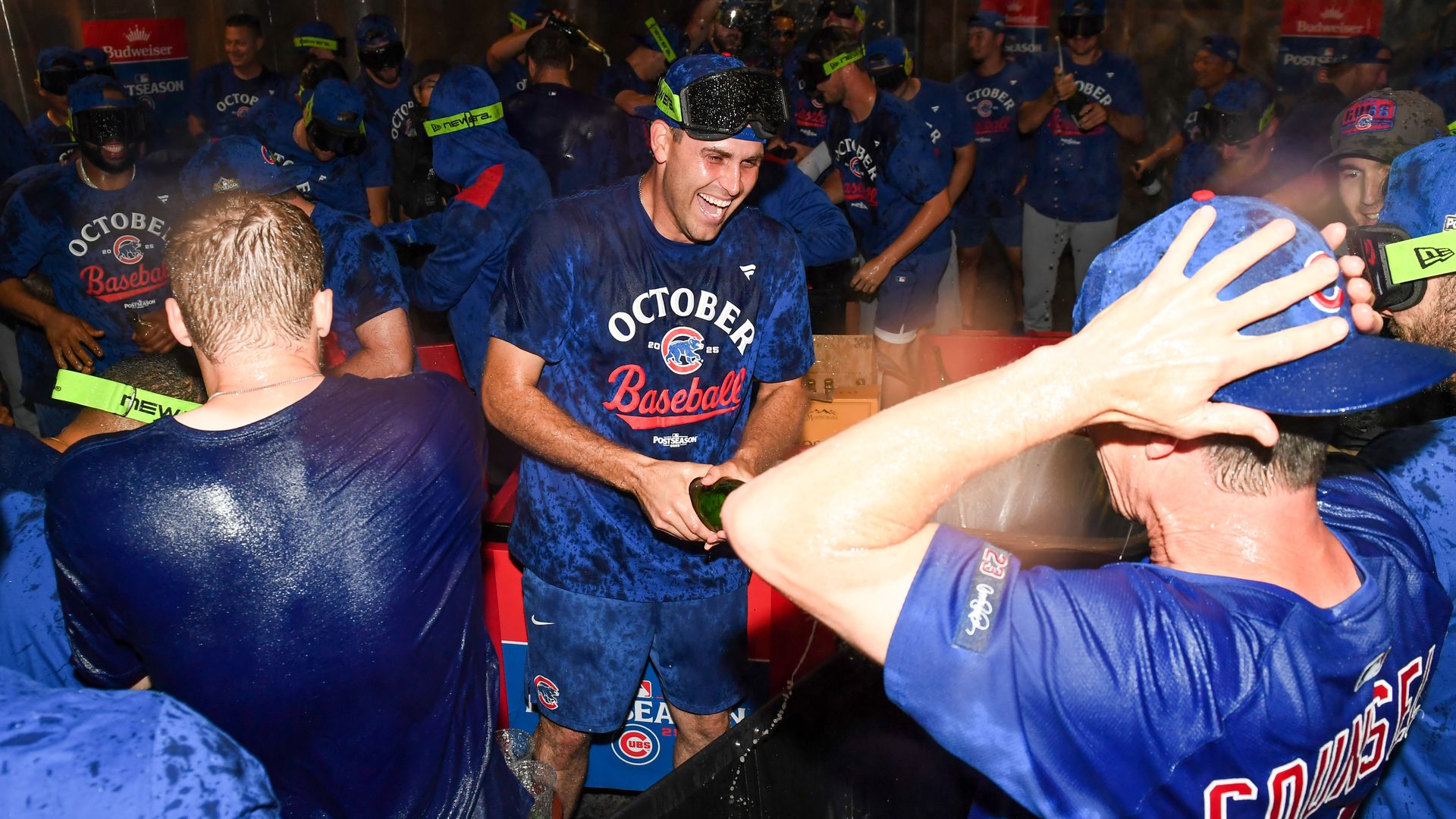 Photo of baseball players in blue shirts spraying bottles of champagne on each other in celebration. 