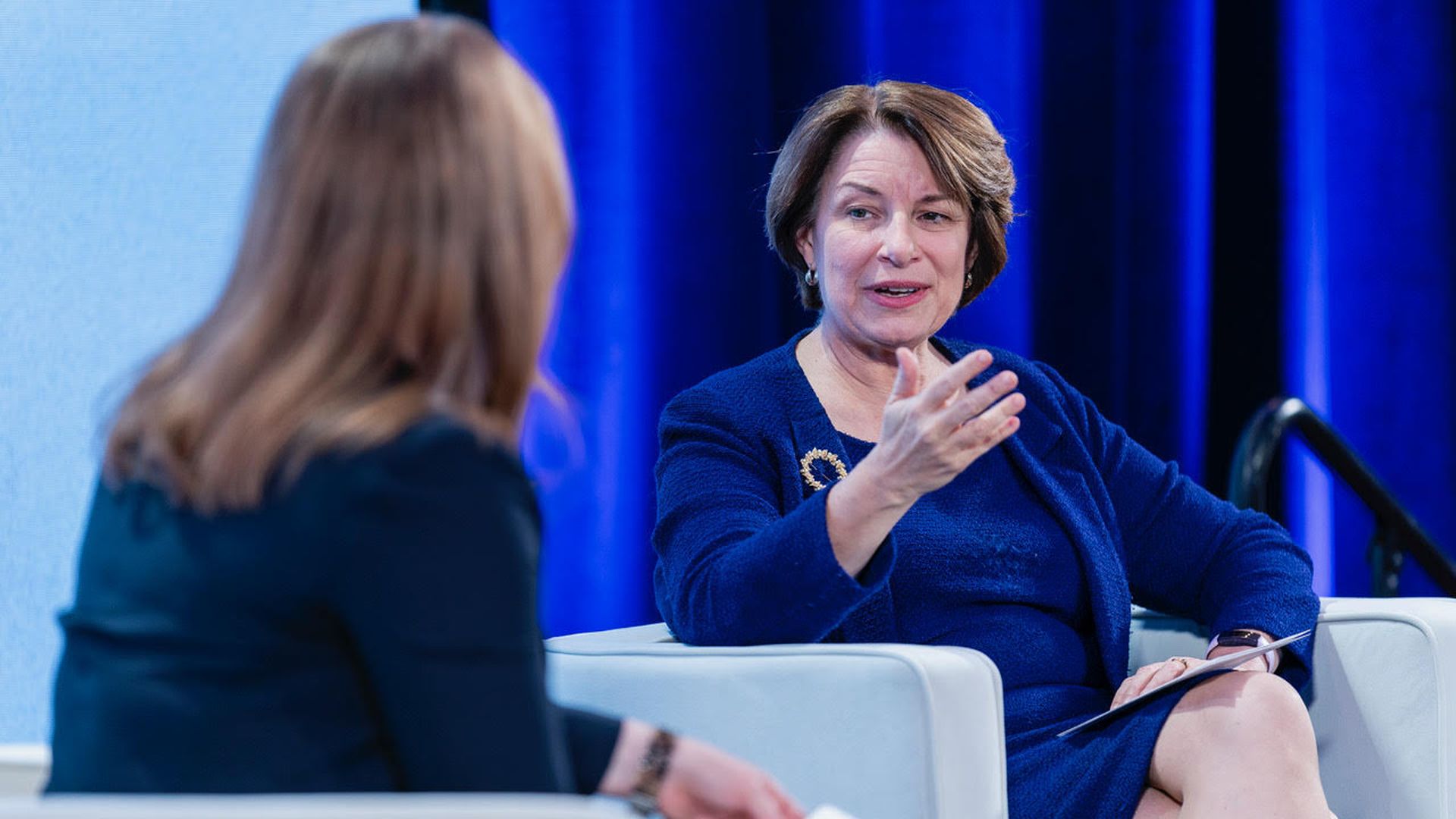 Senator Amy Klobuchar sitting in a chair being interviewed by Ashley Gold from Axios