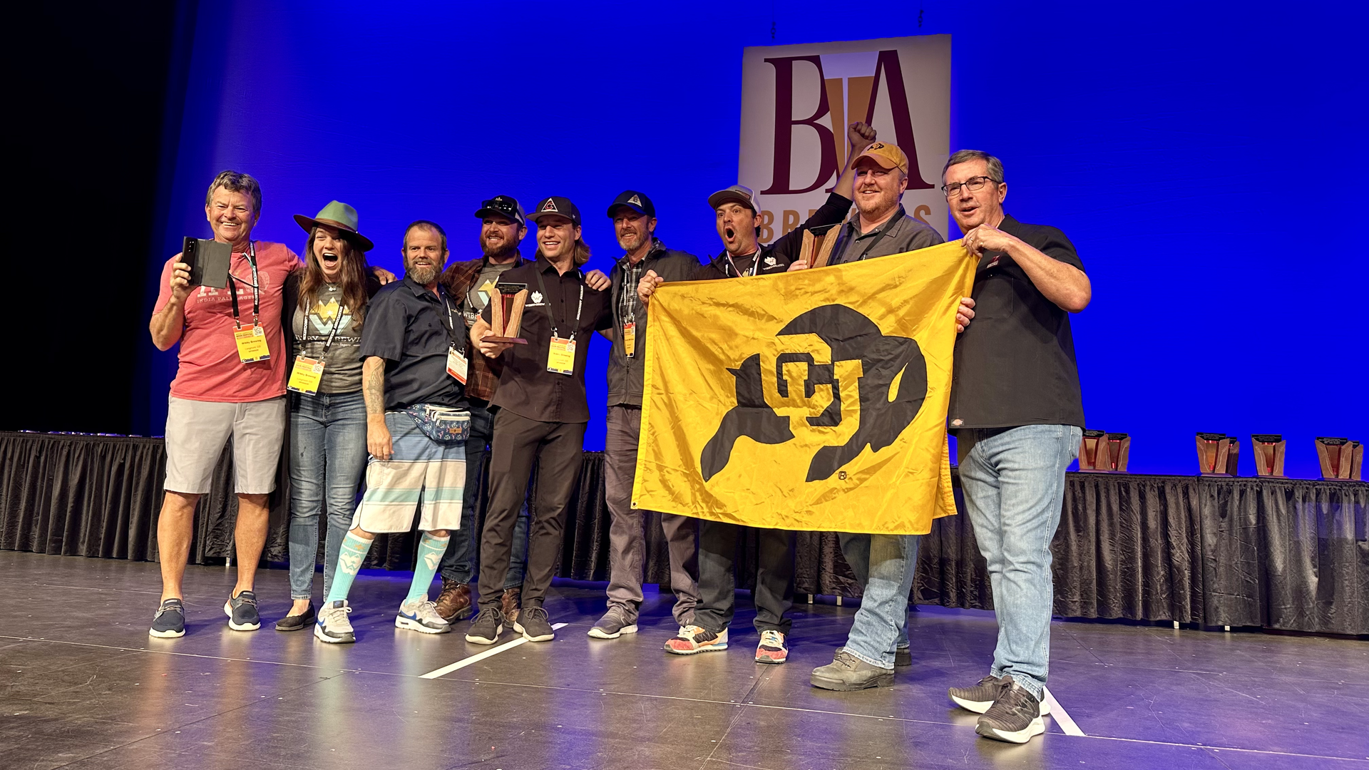 Wibby Brewing staff hold a University of Colorado flag as they accept their Great American Beer Festival trophy on Saturday in Denver. Photo: John Frank/Axios