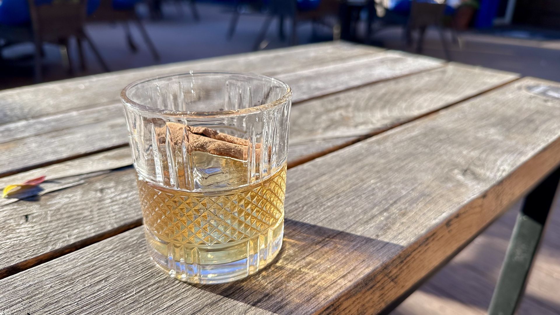 A clear glass of amber liquid on a wooden table on a sunny day