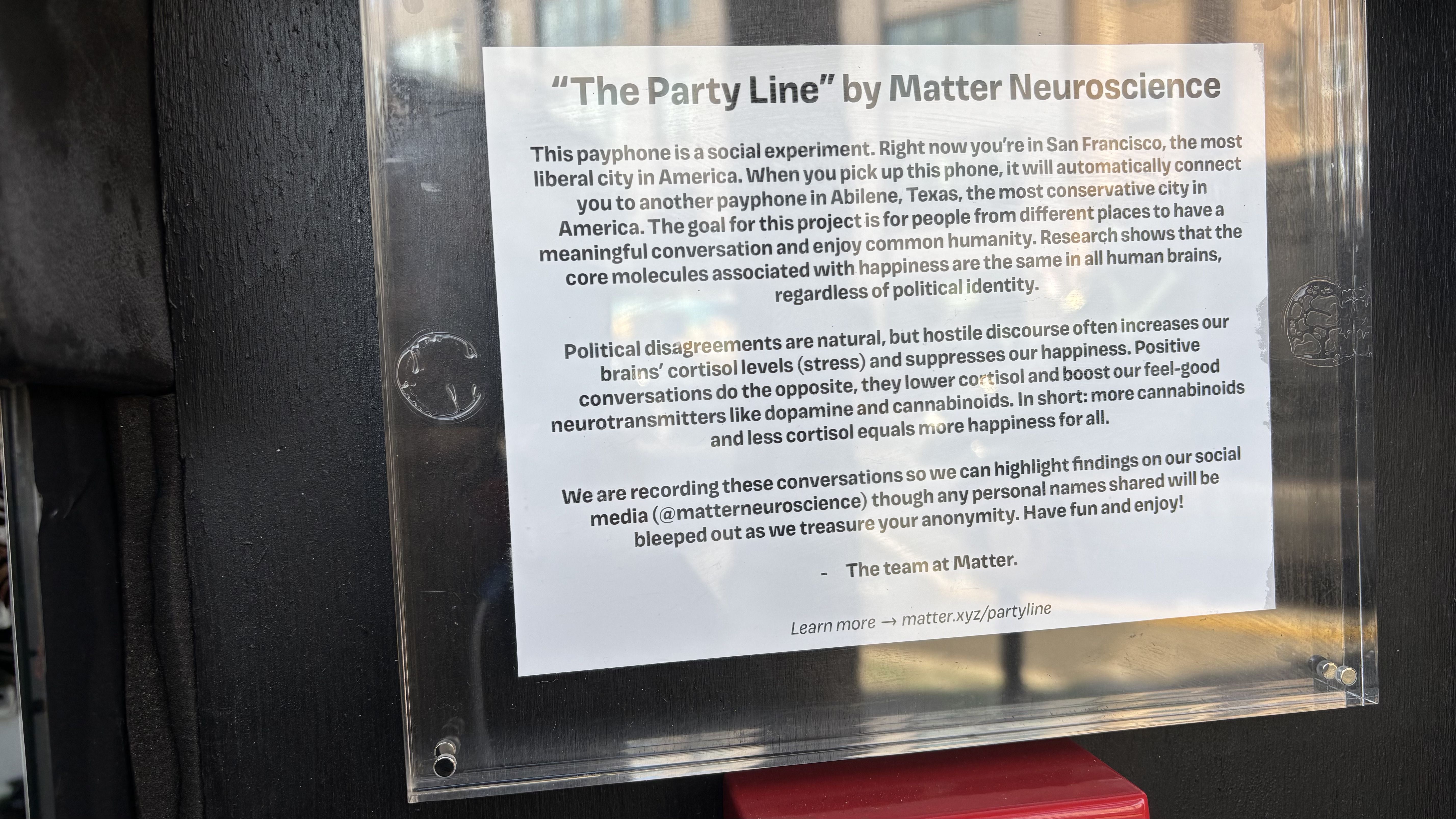 Notice titled "The Party Line" by Matter Neuroscience on a clear board describes a payphone social experiment connecting San Francisco and Abilene, Texas, promoting positive cross-political conversations.
