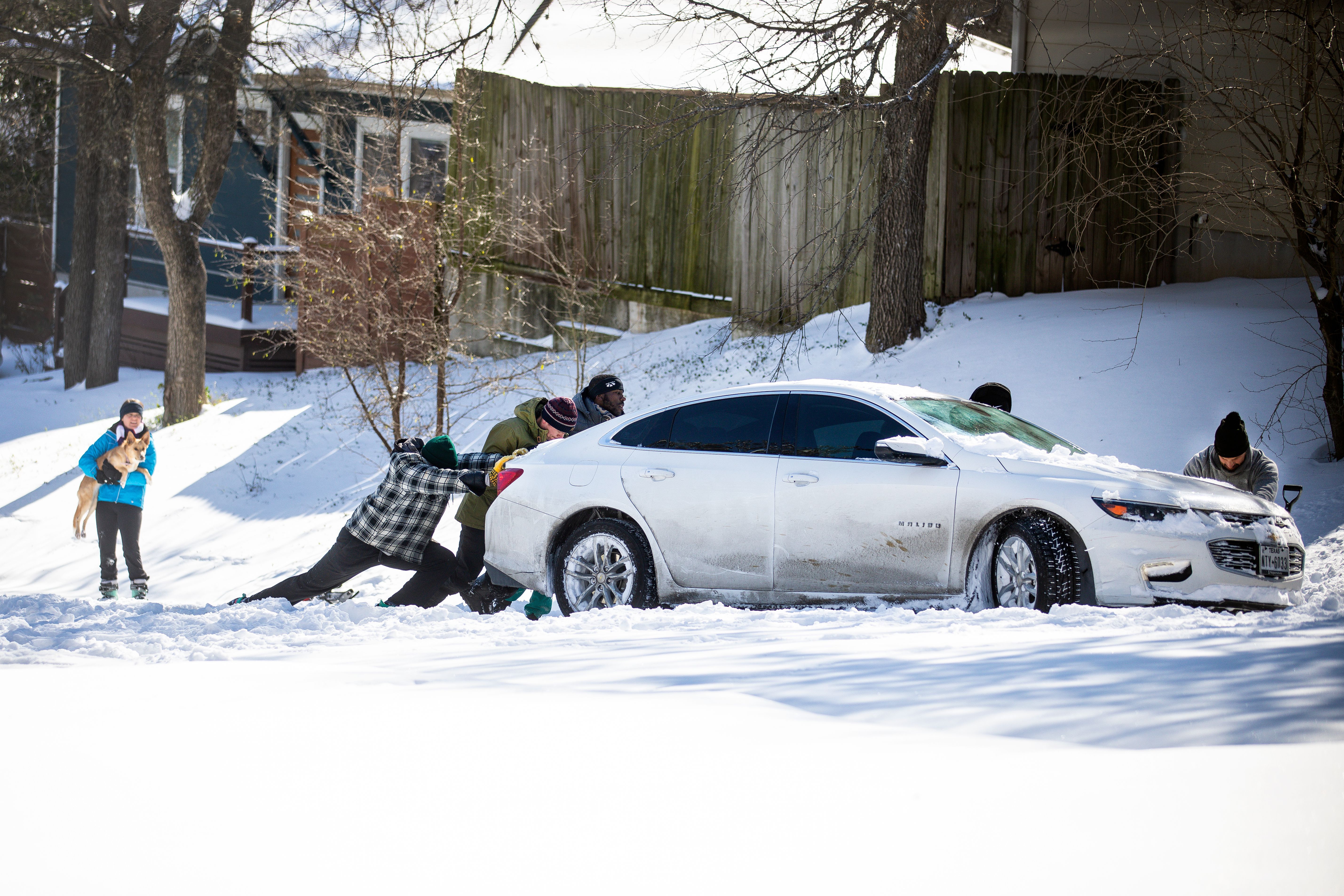 People push a car out of the snow in Austin, Texas. 