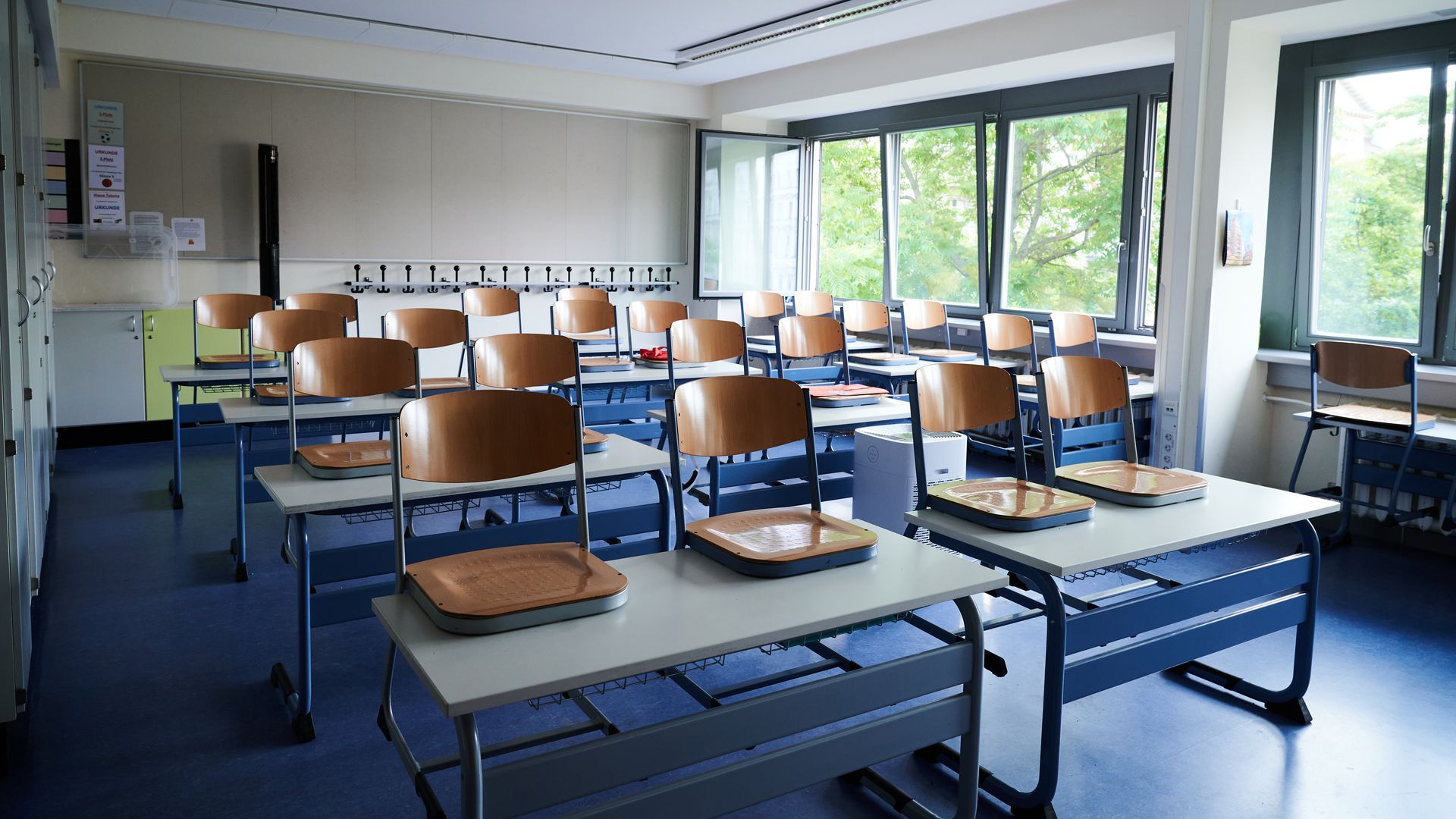 Empty school desks and chairs stacked on top in a classroom.