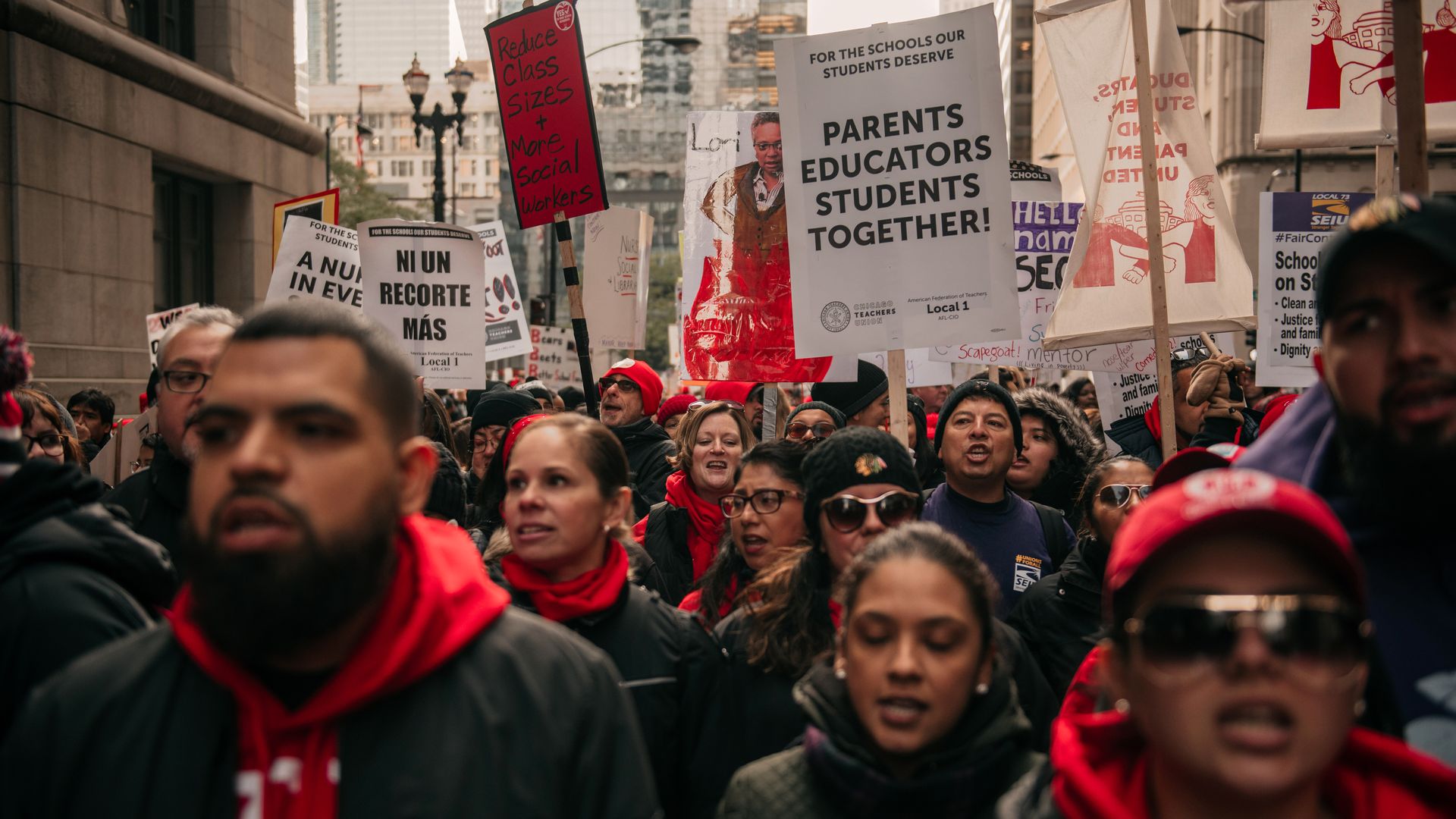 In this image, teachers on strike carry signs that read "Parents educators students together!" 