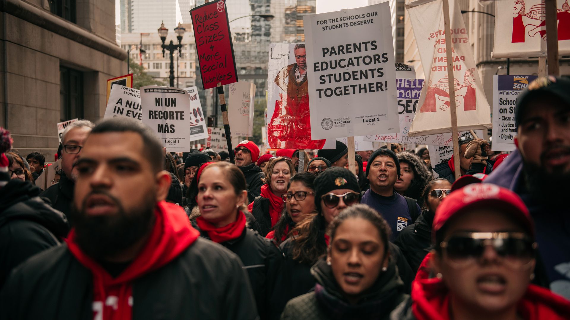In this image, teachers on strike carry signs that read "Parents educators students together!"