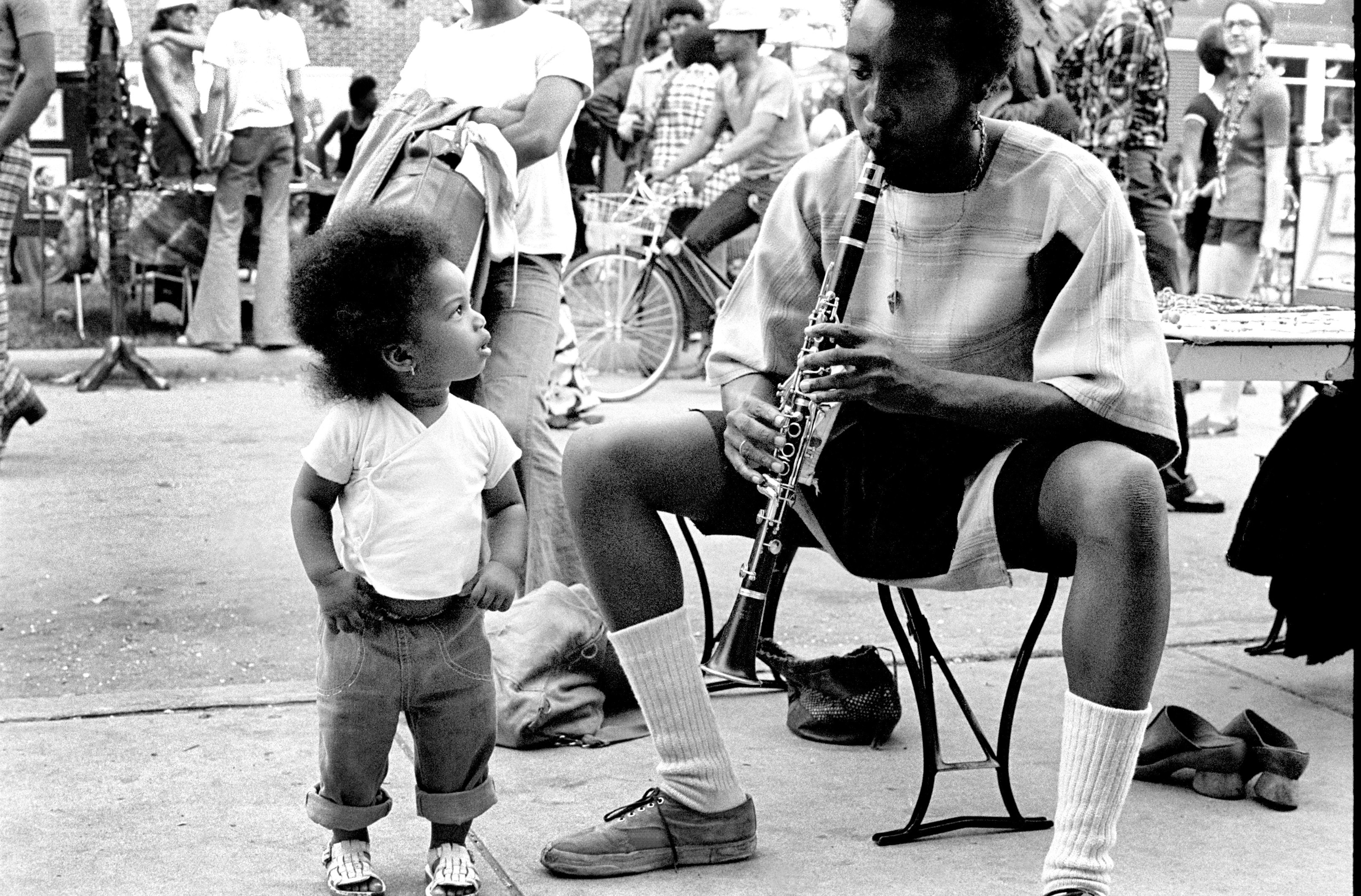 Photo of a baby staring at a man playing the clarinet 