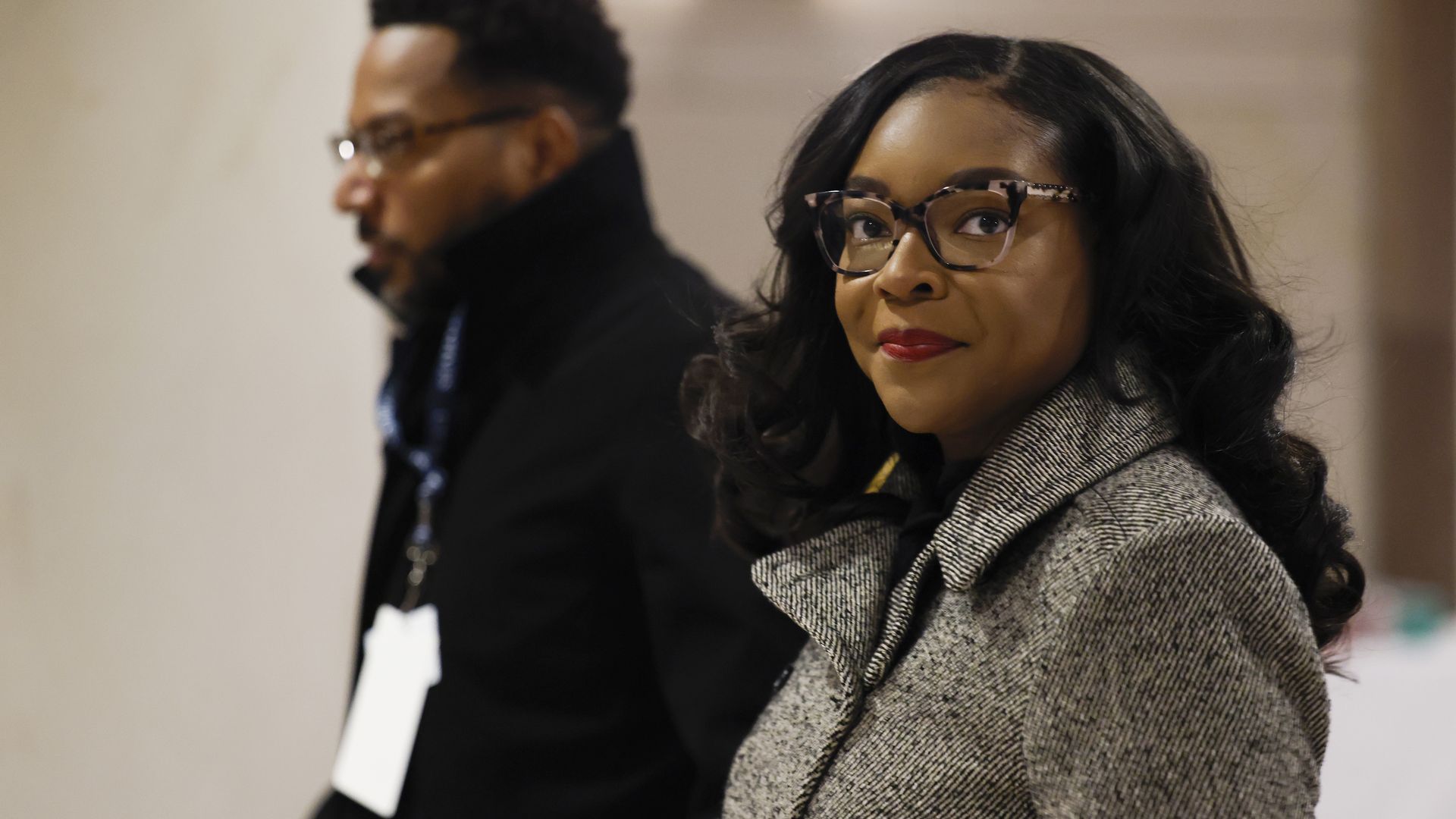 Black woman in glasses and herringbone coat