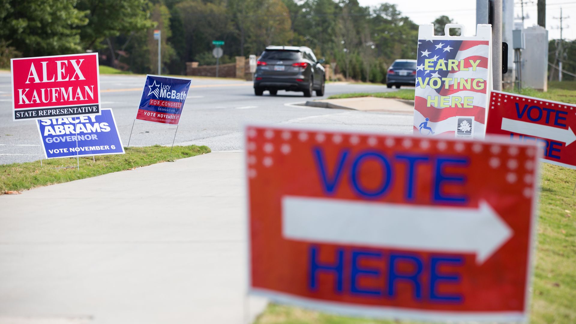 Red White and Blue Vote Here sign and Stacey Abrams picket sign in background.