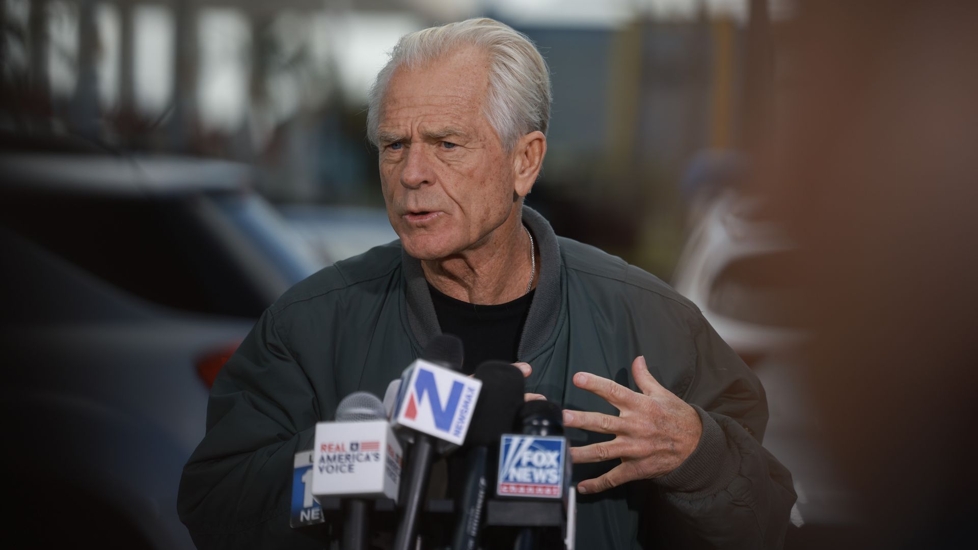 Peter Navarro speaks into microphones of several news outlets 
