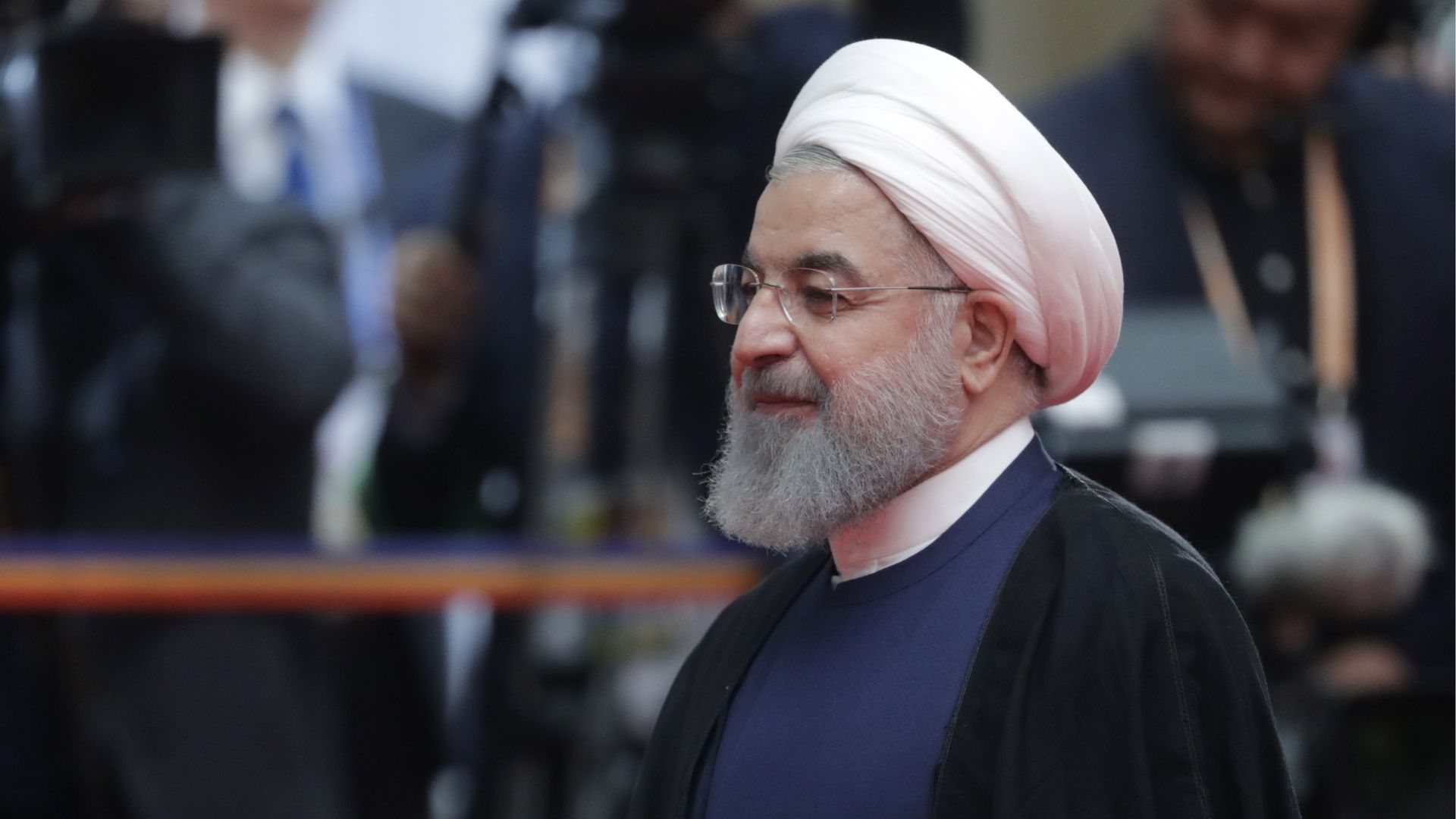 Iranian President Hassan Rouhani walks by photographers