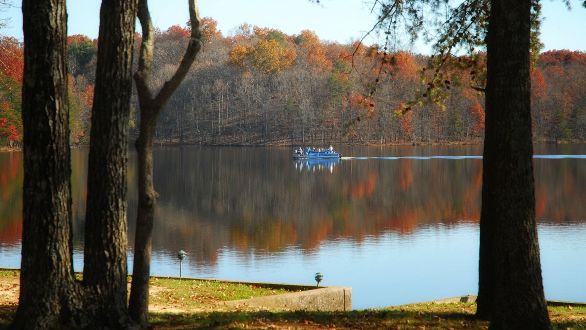 A blue boat glides along the river of Fall Creek Falls State Park in fall.