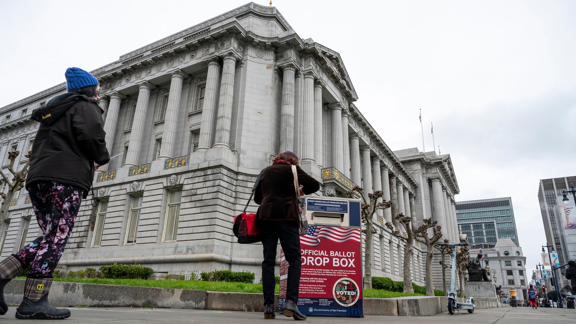 two people walk up to voting drop box outside city hall