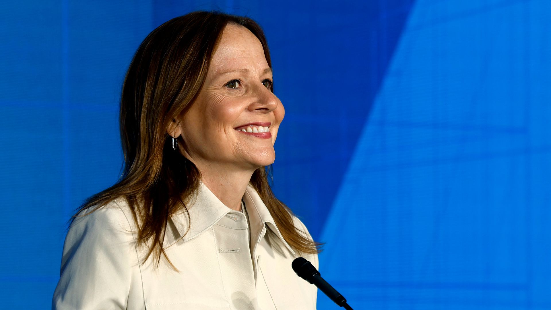 A woman smiles while looking into a crowd from a stage.