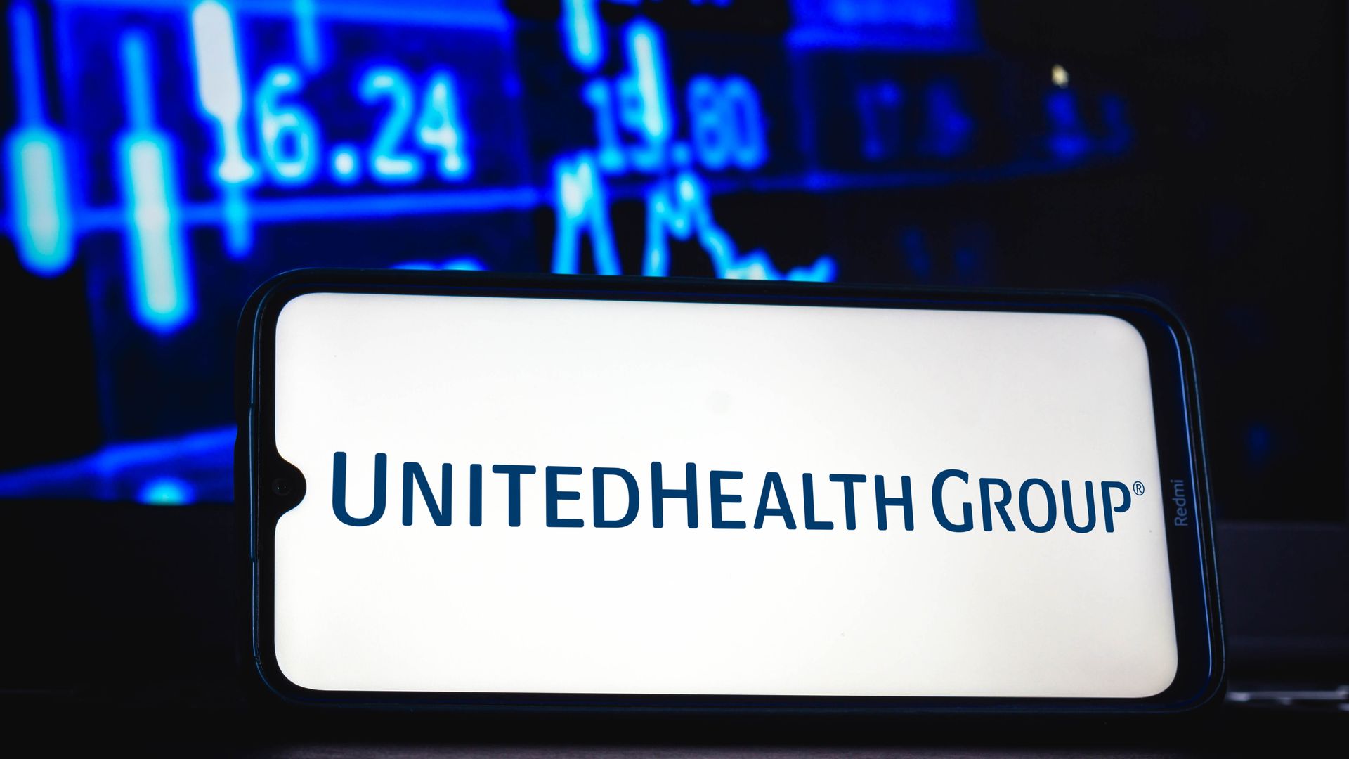 Blue UnitedHealth Group logo on a white phone with blue numbers in the background.