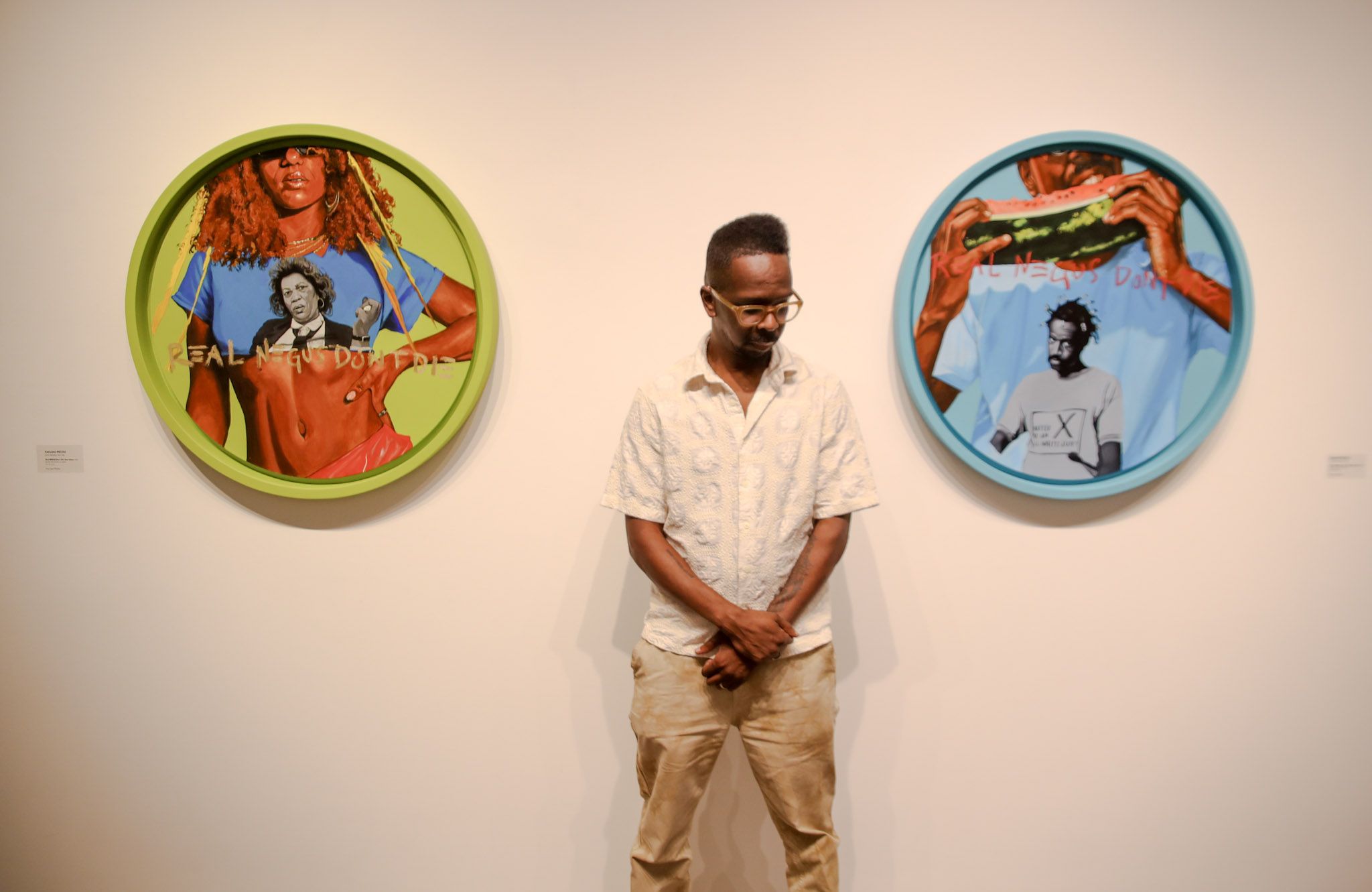Artist Fahamu Pecou stands between two powerful portraits from his We The Roses exhibition, capturing themes of Black resilience and identity. Photo: Malcolm K. Porter