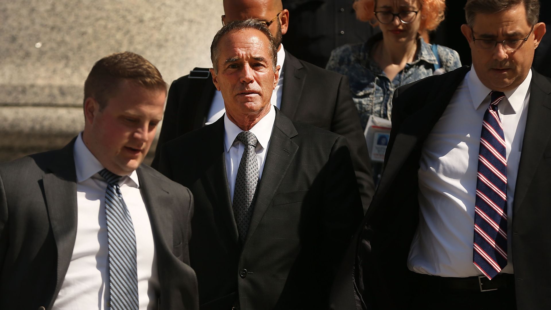 Rep. Chris Collins walking out of a court house surrounded by body guards 