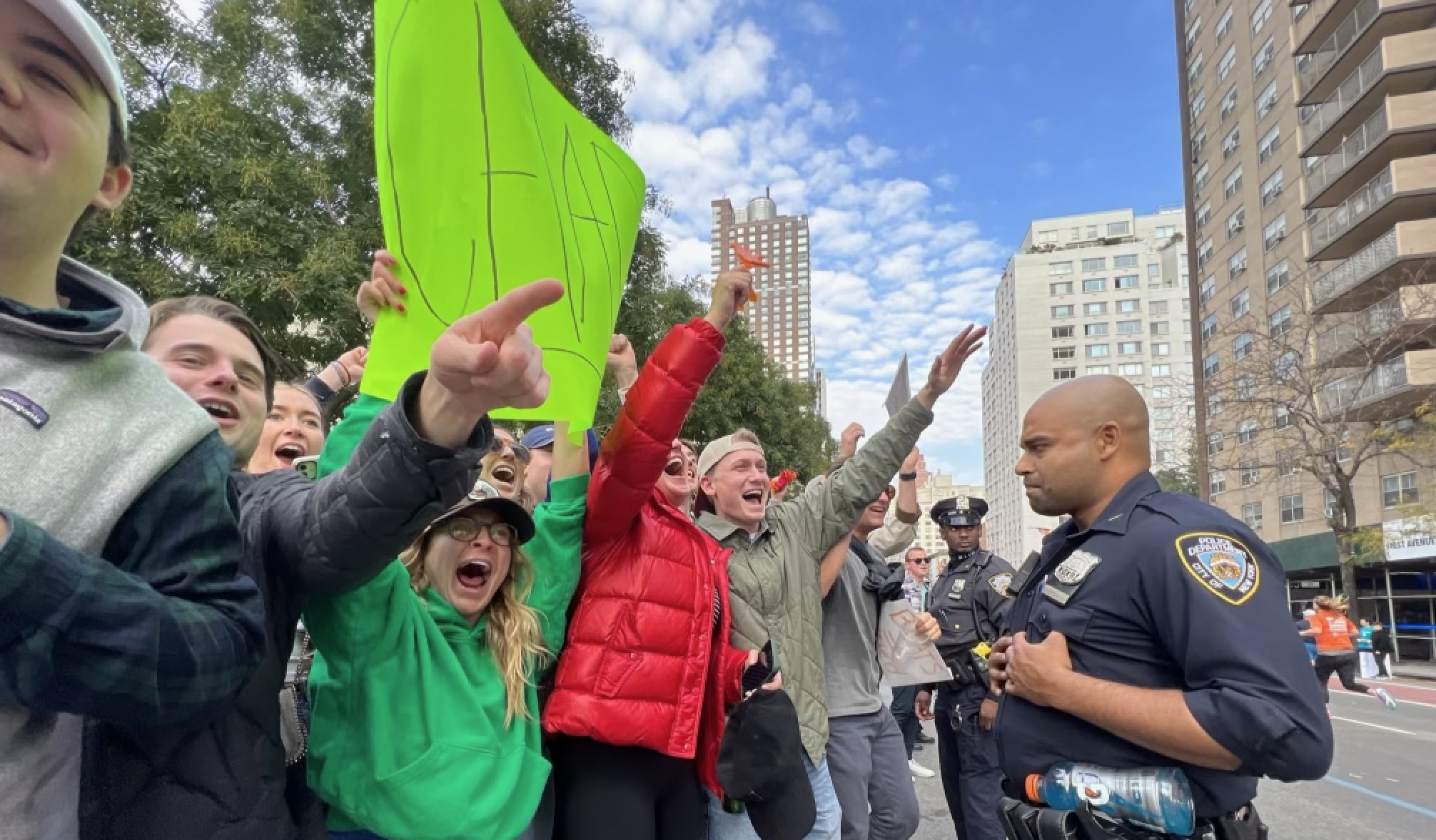 a photo of a crowd cheering on runners while a police officer looks on.