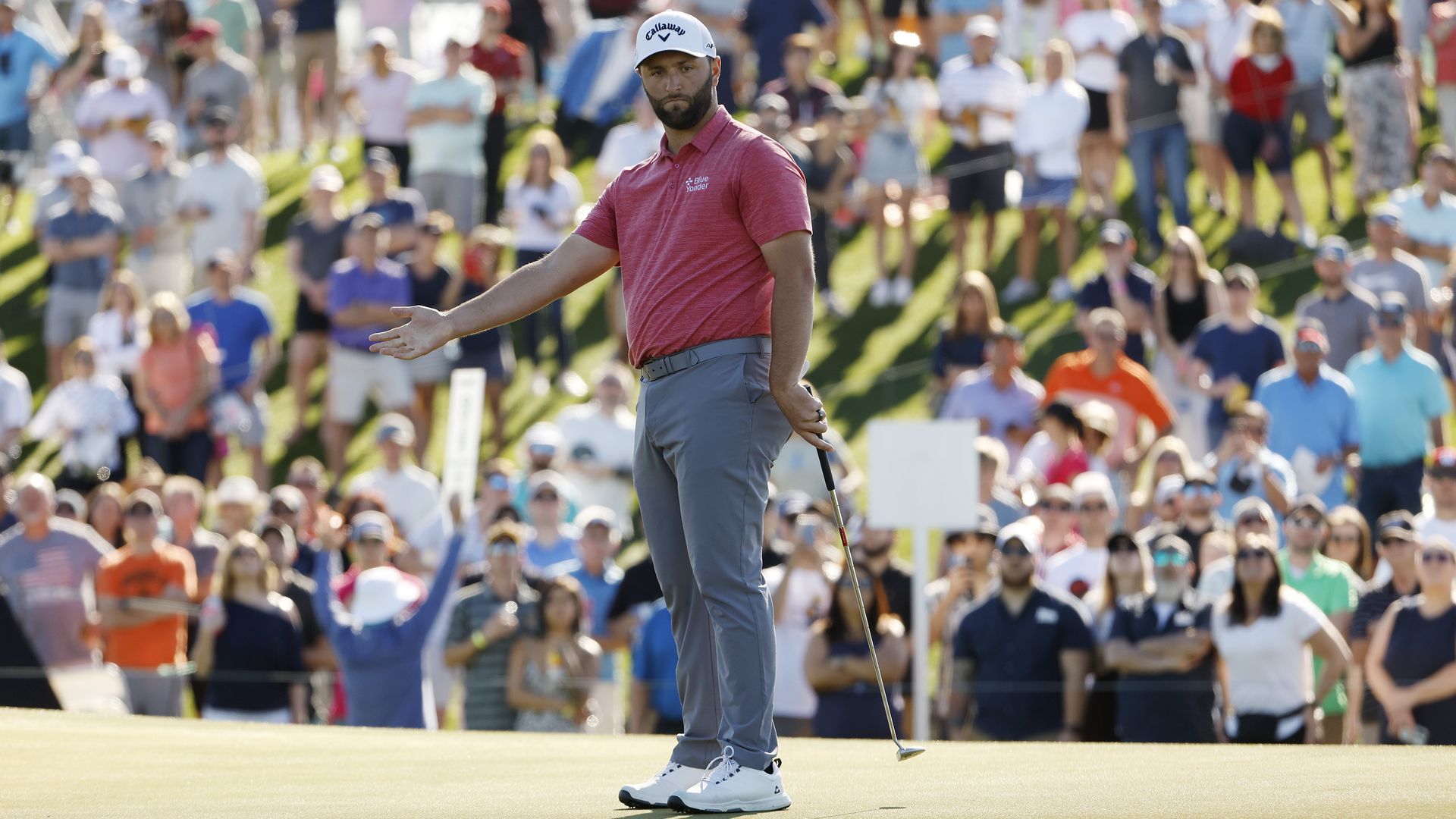 A golfer on the green with a large crowd in the background. 