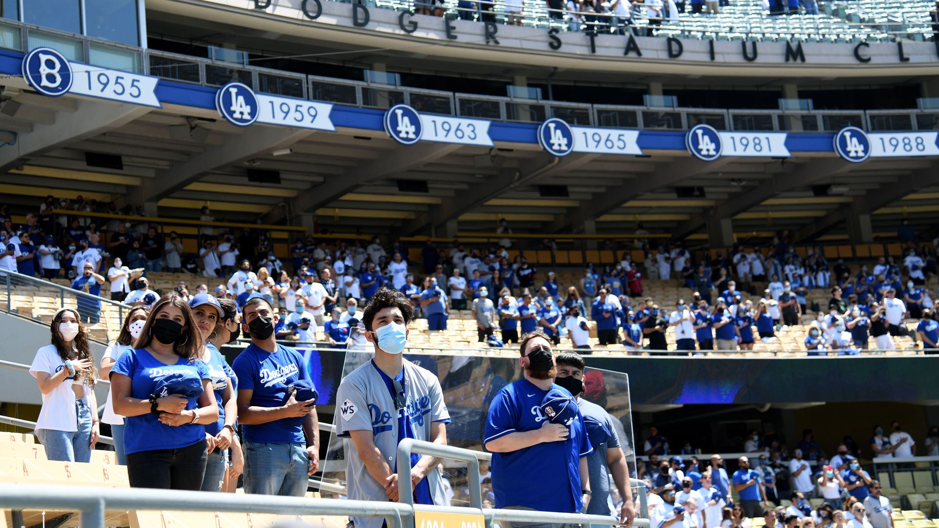 People wearing masks standing for the national anthem at Dodgers Stadium.