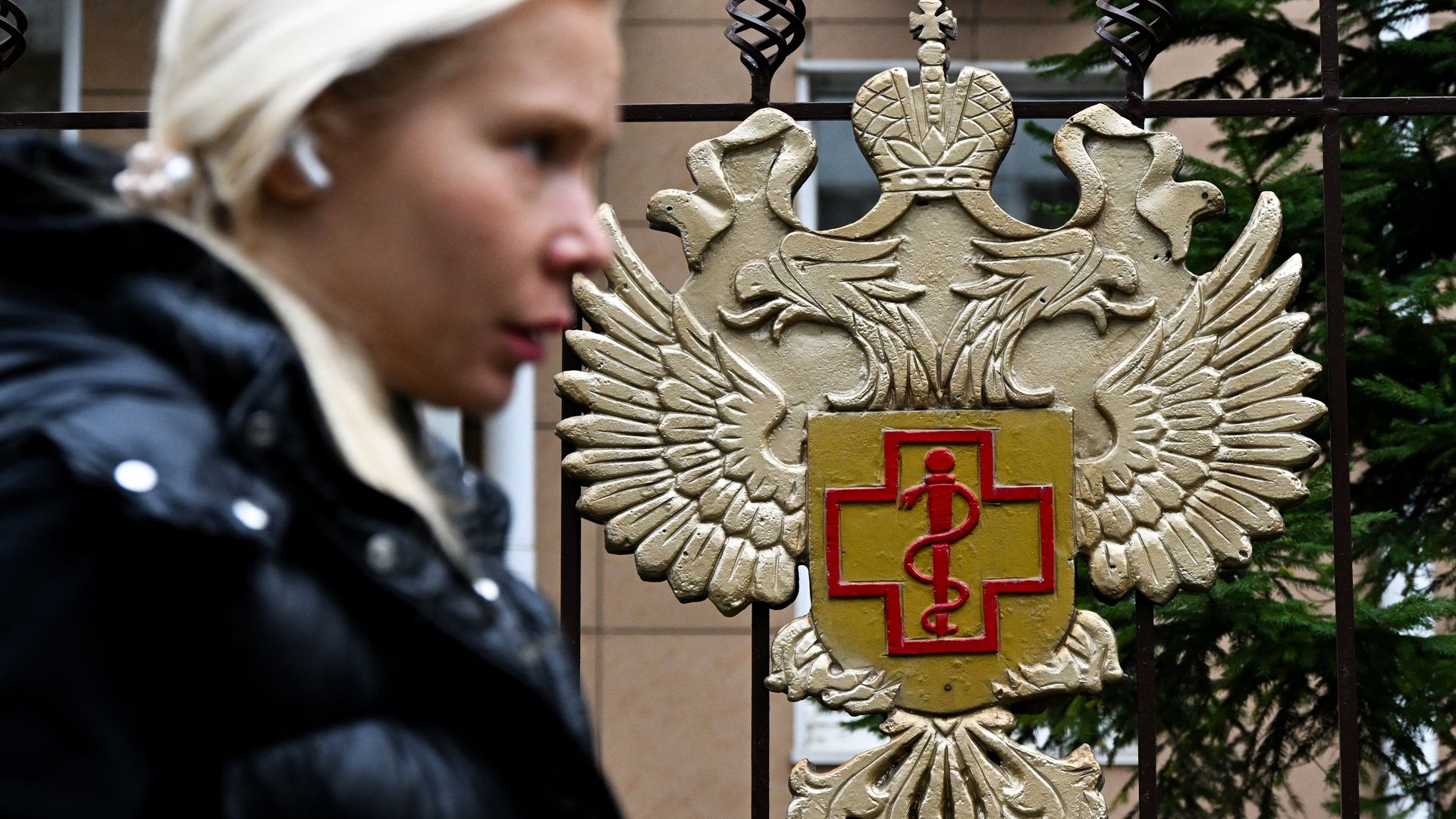 A woman walks past the Rospotrebnadzor logo on fencing outside the Russian health watchdog’s headquarters in Moscow.