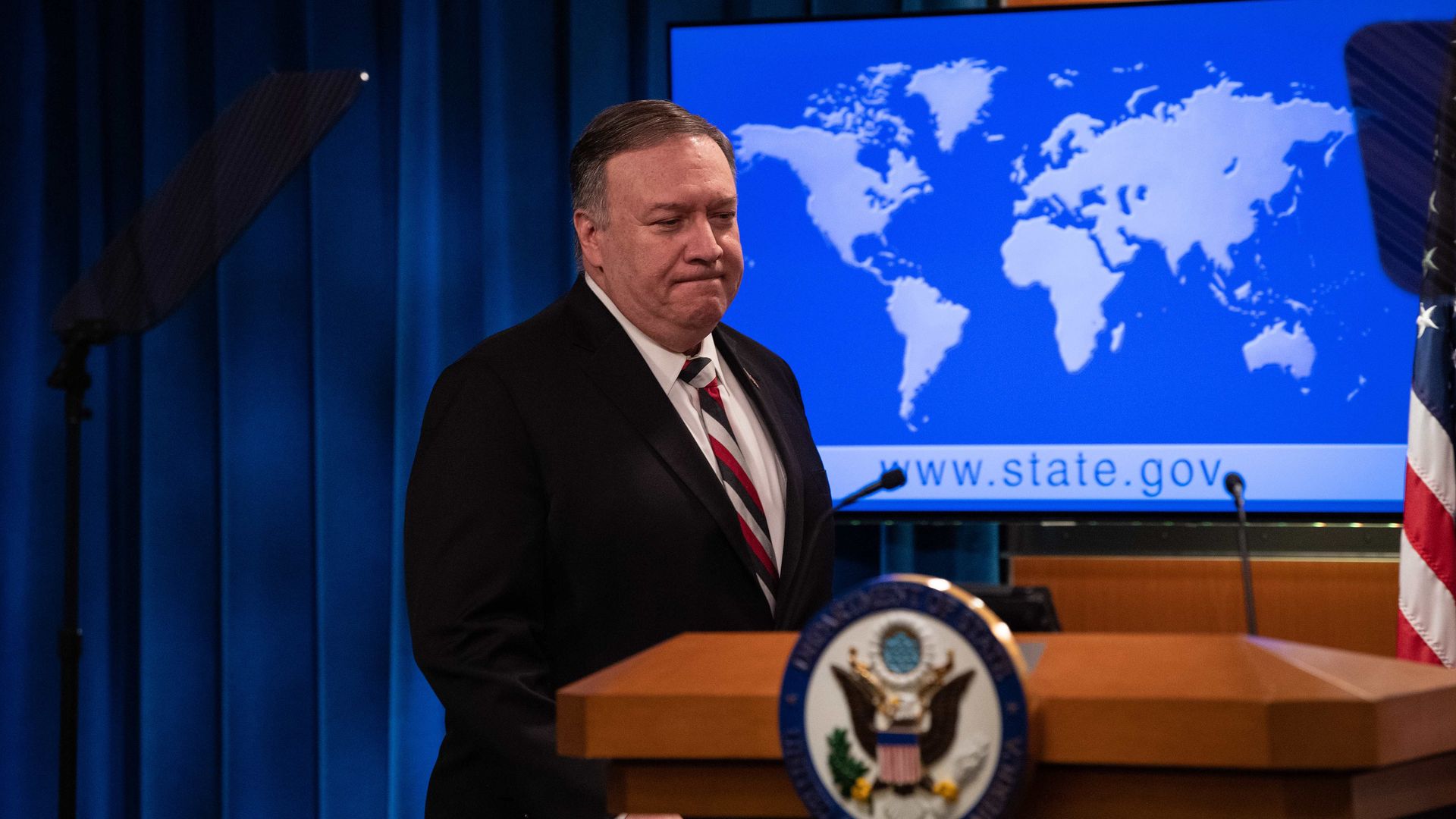 In this image, Mike Pompeo stands in front of a map of the world