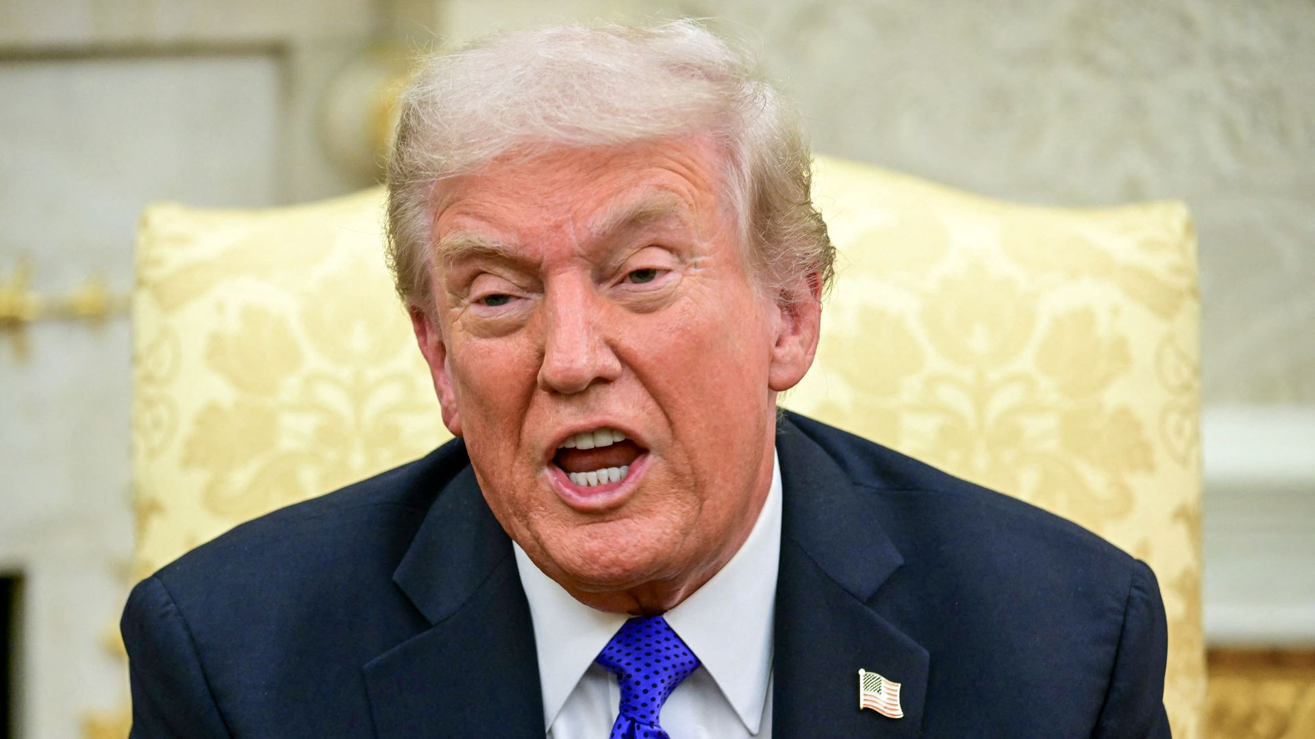 President Trump, seated in a gold chair and speaking to reporters. 