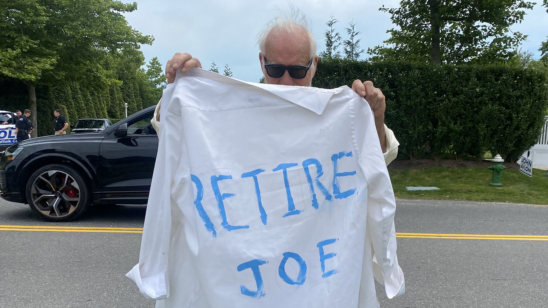 Man outside Biden fundraiser holds shirt that says "Retire Joe"