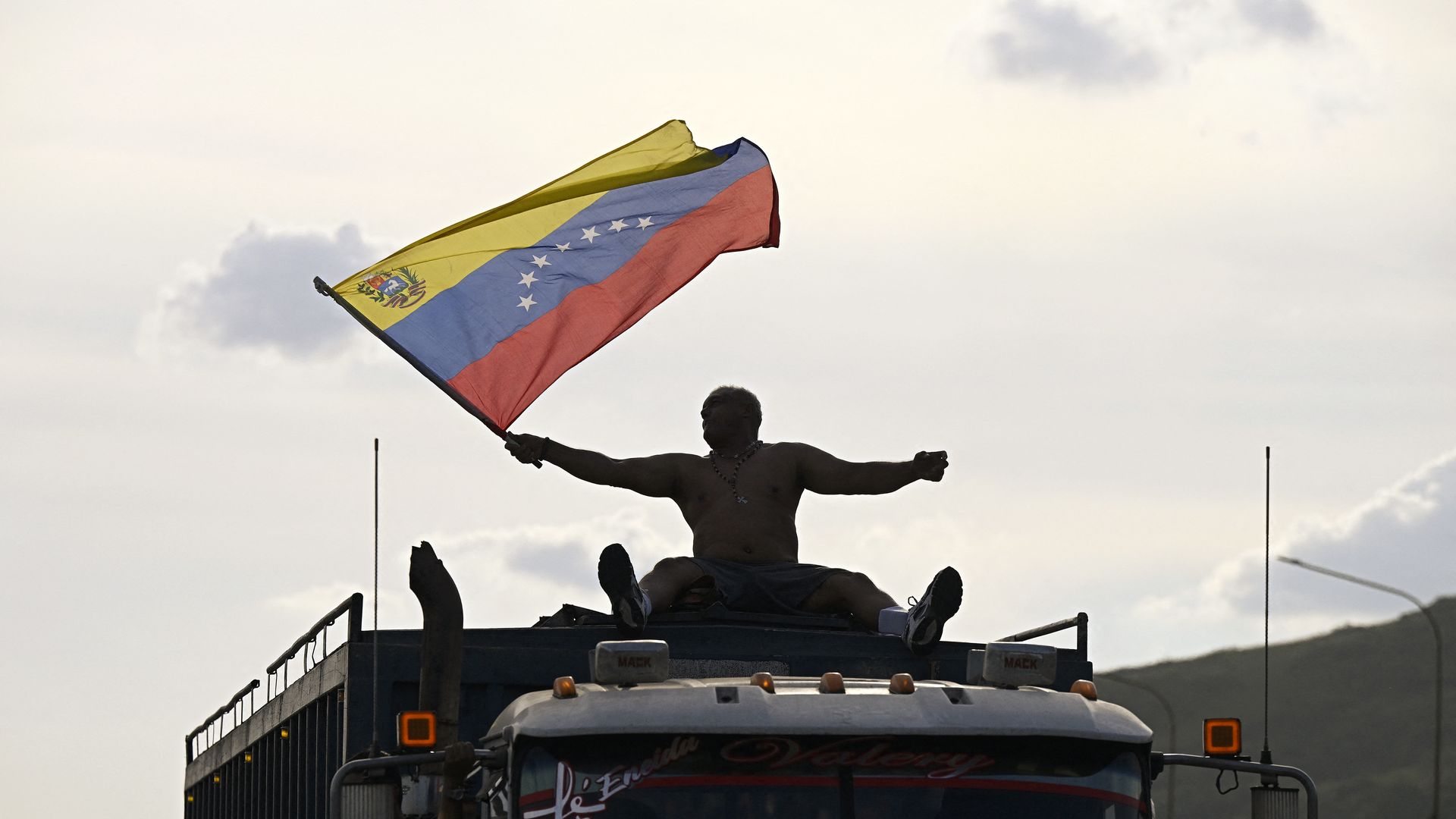 A demonstrator waves a Venezuelan flag atop a vehicle.