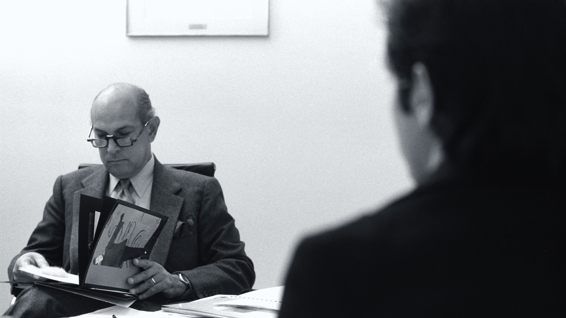 Photo of a man looking through a binder at a desk