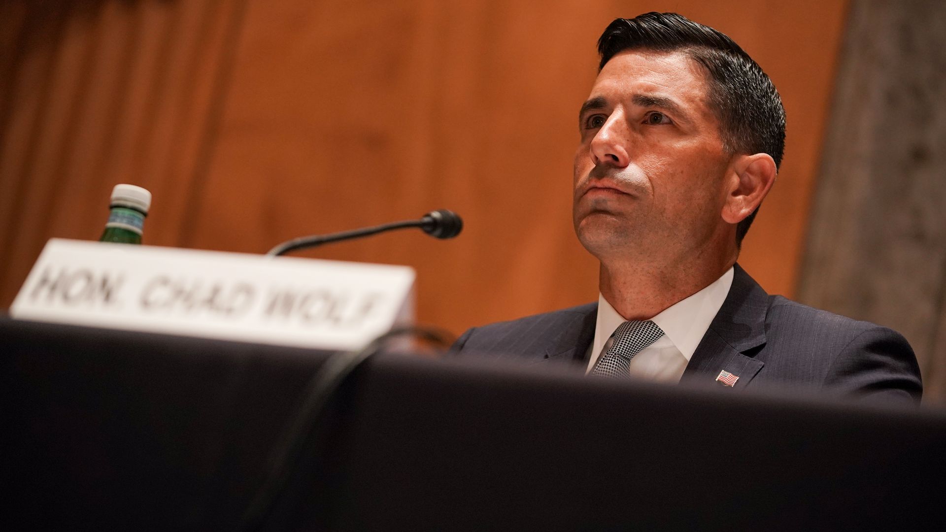Chad Wolf sits in front of a microphone 