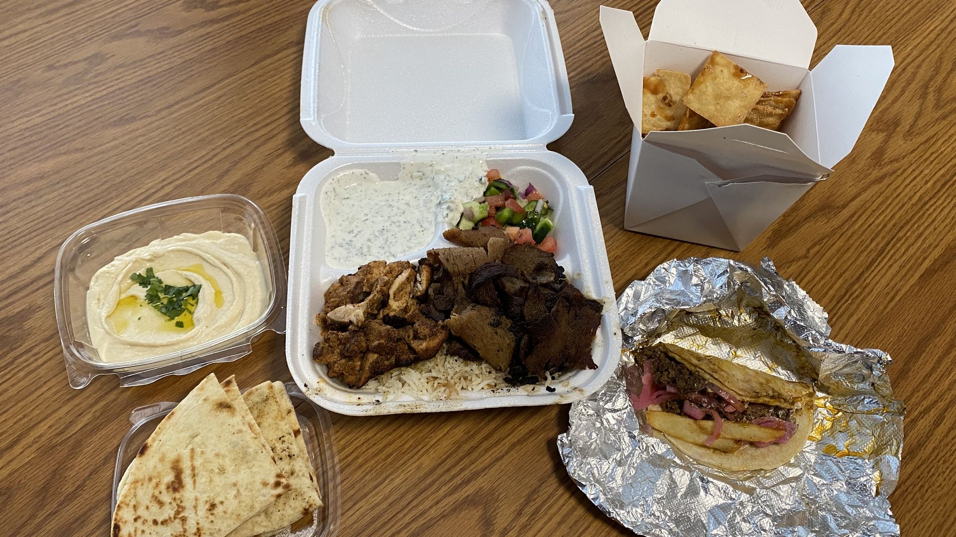 Food in takeout containers on a table from a Mexican Mediterranean fusion food truck