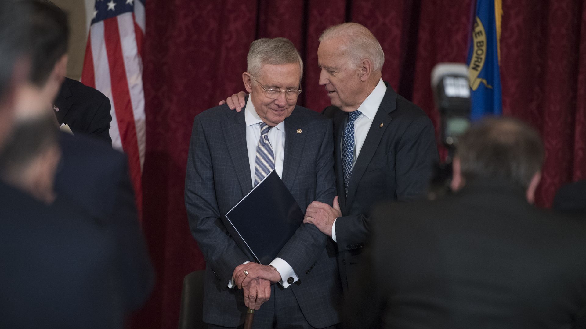 Photo of Joe Biden embracing Harry Reid as photographers face them