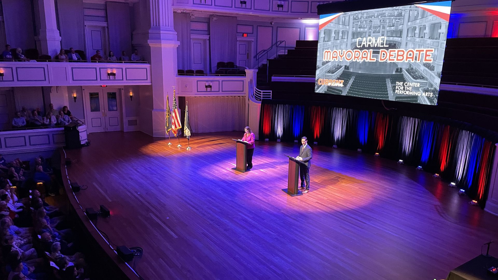 Republican Sue Finkam, left, and Democrat Miles Nelson stand at lecterns and prepare to debate at the Palladium at the Center for Performing Arts.