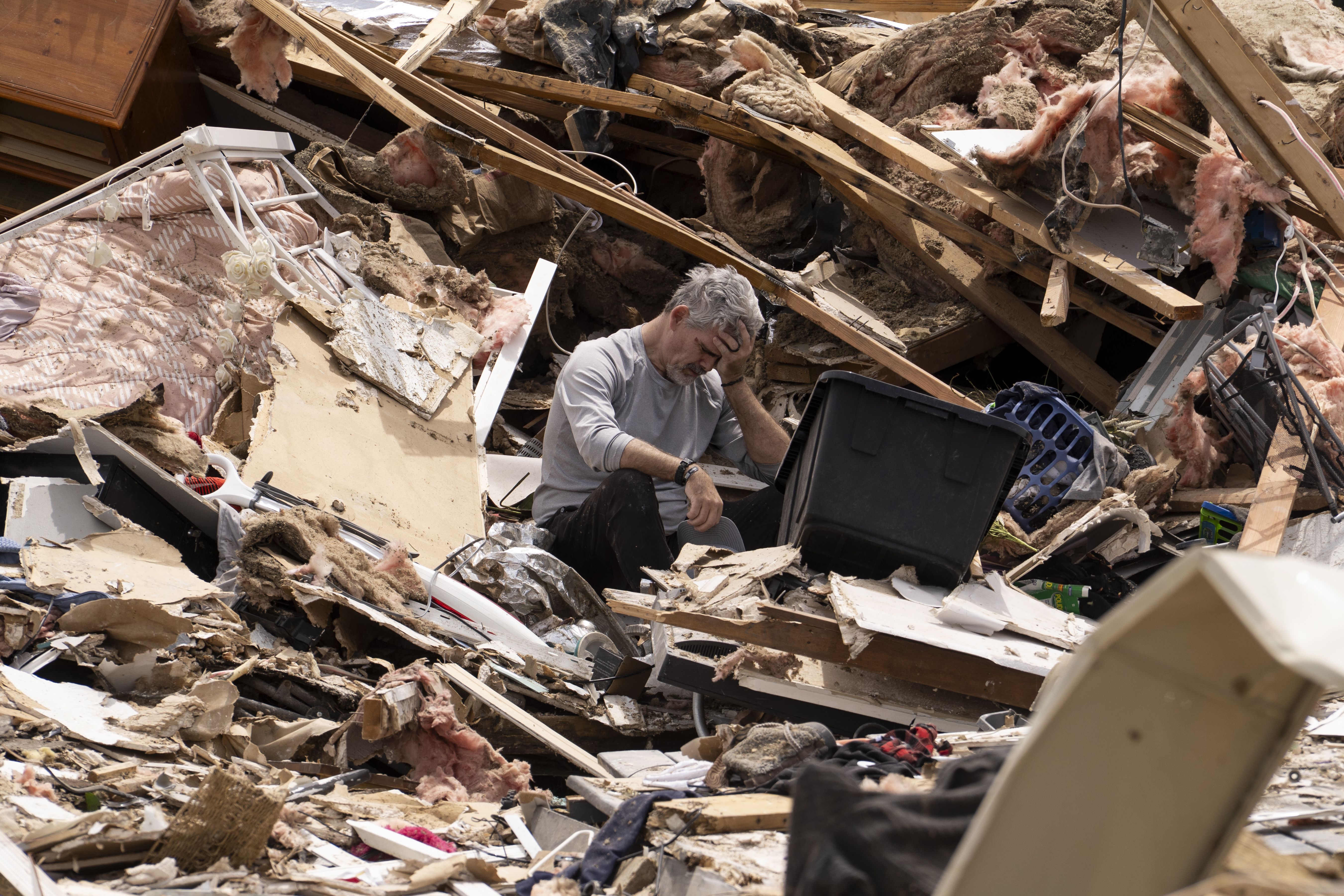A man is overcome by emotions while cleaning up the debris of his house in Kentucky yesterday.