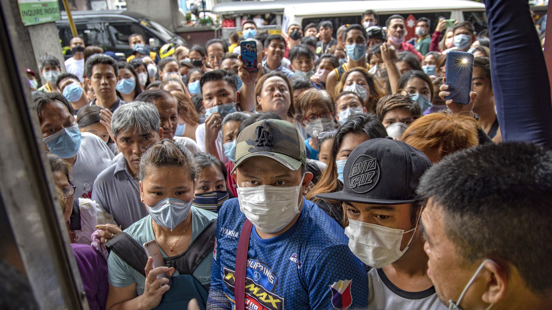  Filipinos hoping to buy face masks crowd outside a medical supply shop that was raided by police for allegedly hoarding and overpricing the masks