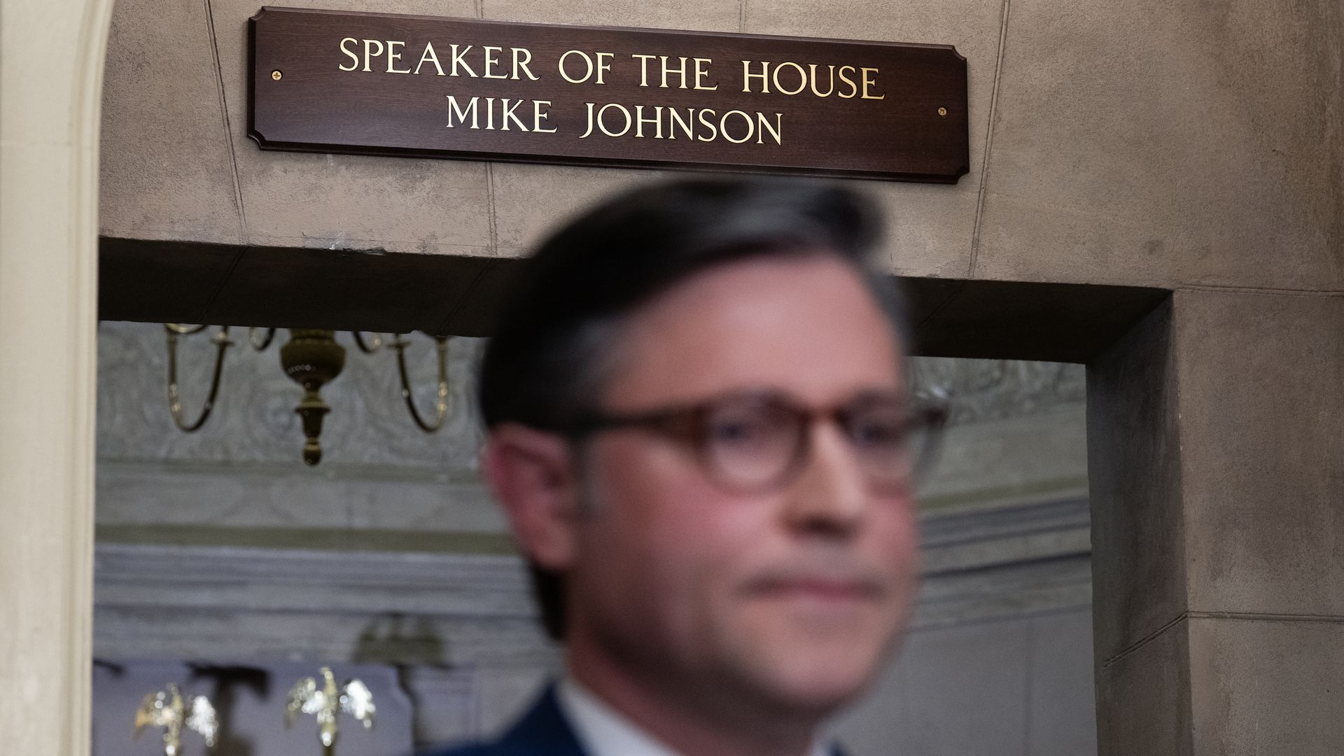 Speaker Johnson outside his office, a sign above him reads "Speaker of the House Mike Johnson" 