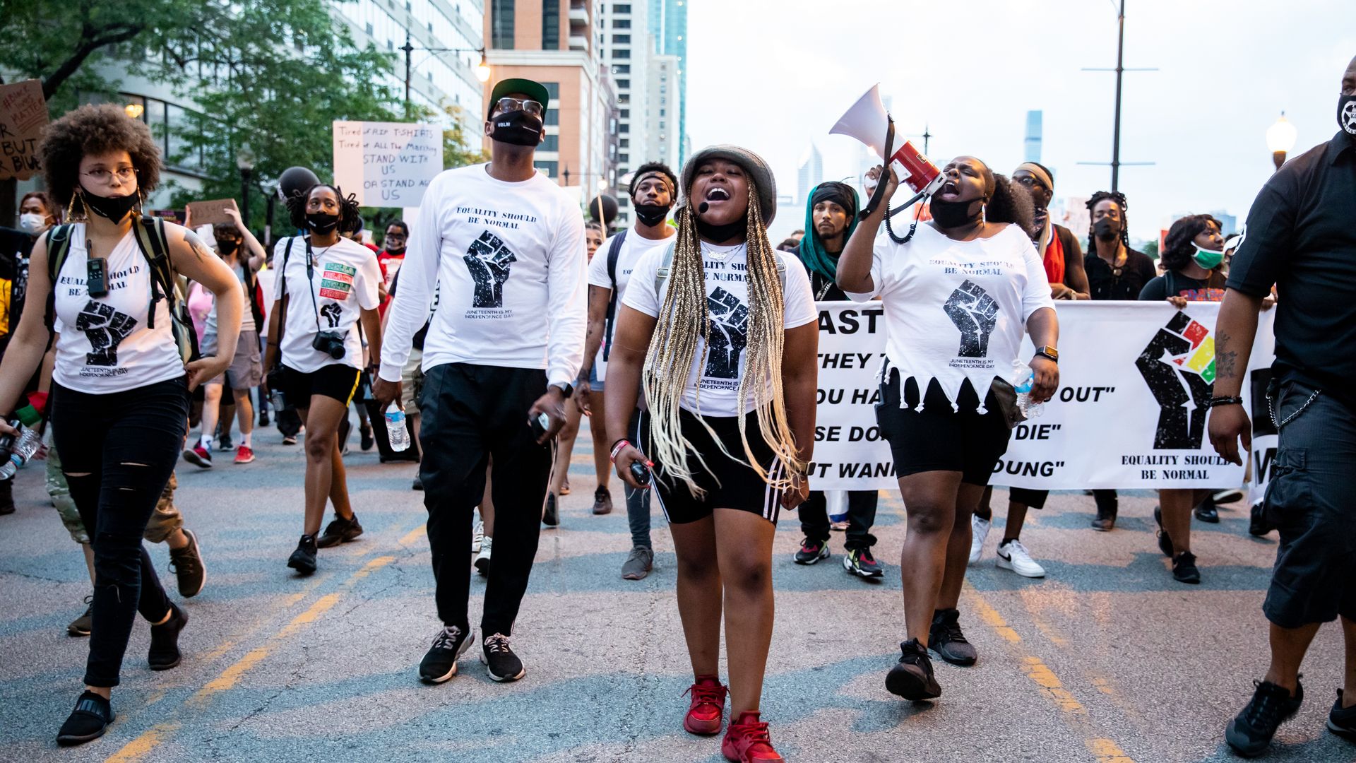 Organizers of the Chicago Peace March lead the march in Chicago while wearing white t-shirt with a printed fist