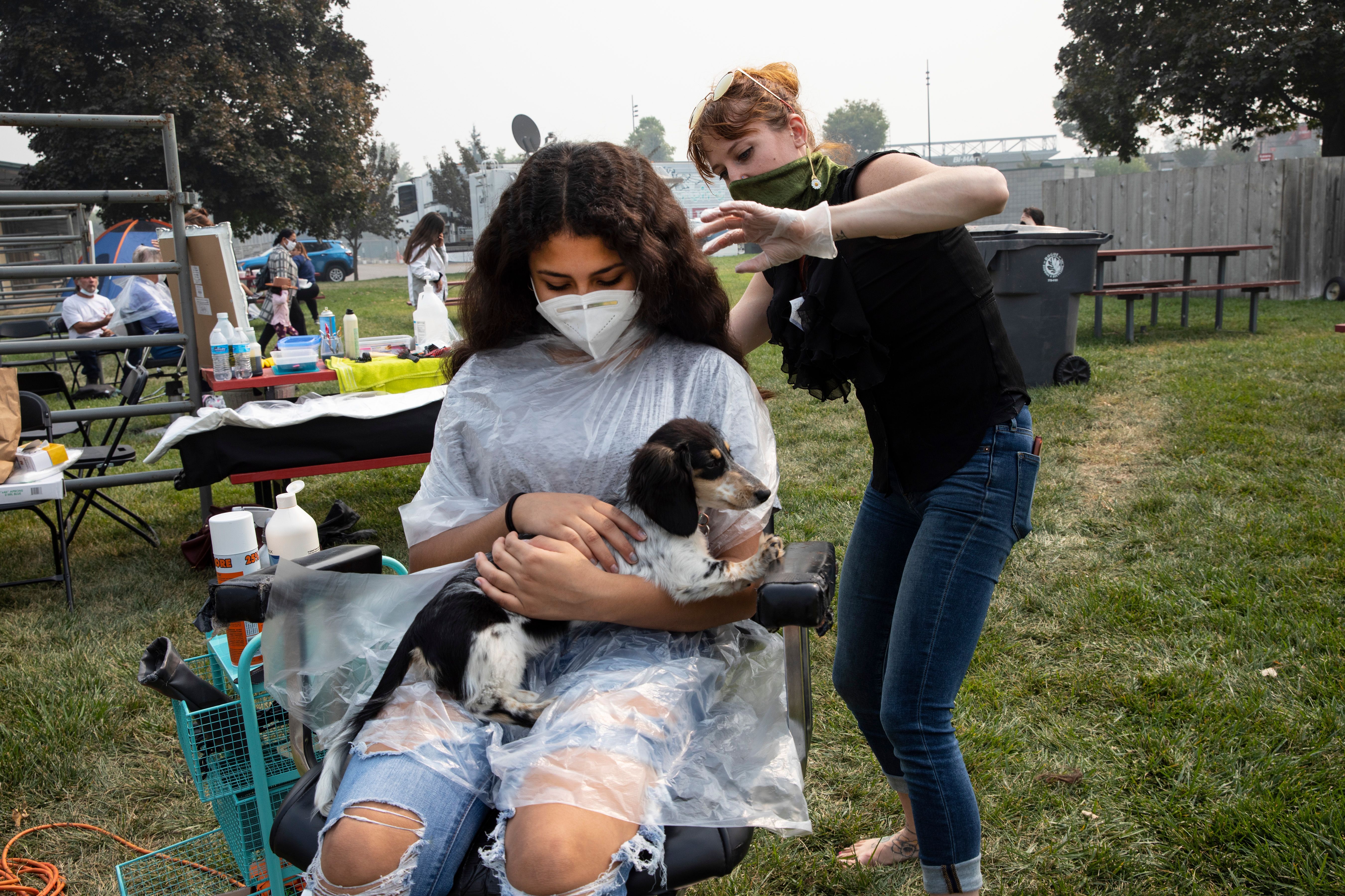 Brissia Rodriguez, 12, gets a free haircut from hairdresser Donnye Sabo, owner of Boho Bella Salon, at the evacuation center at the Jackson County Fairgrounds on September 16