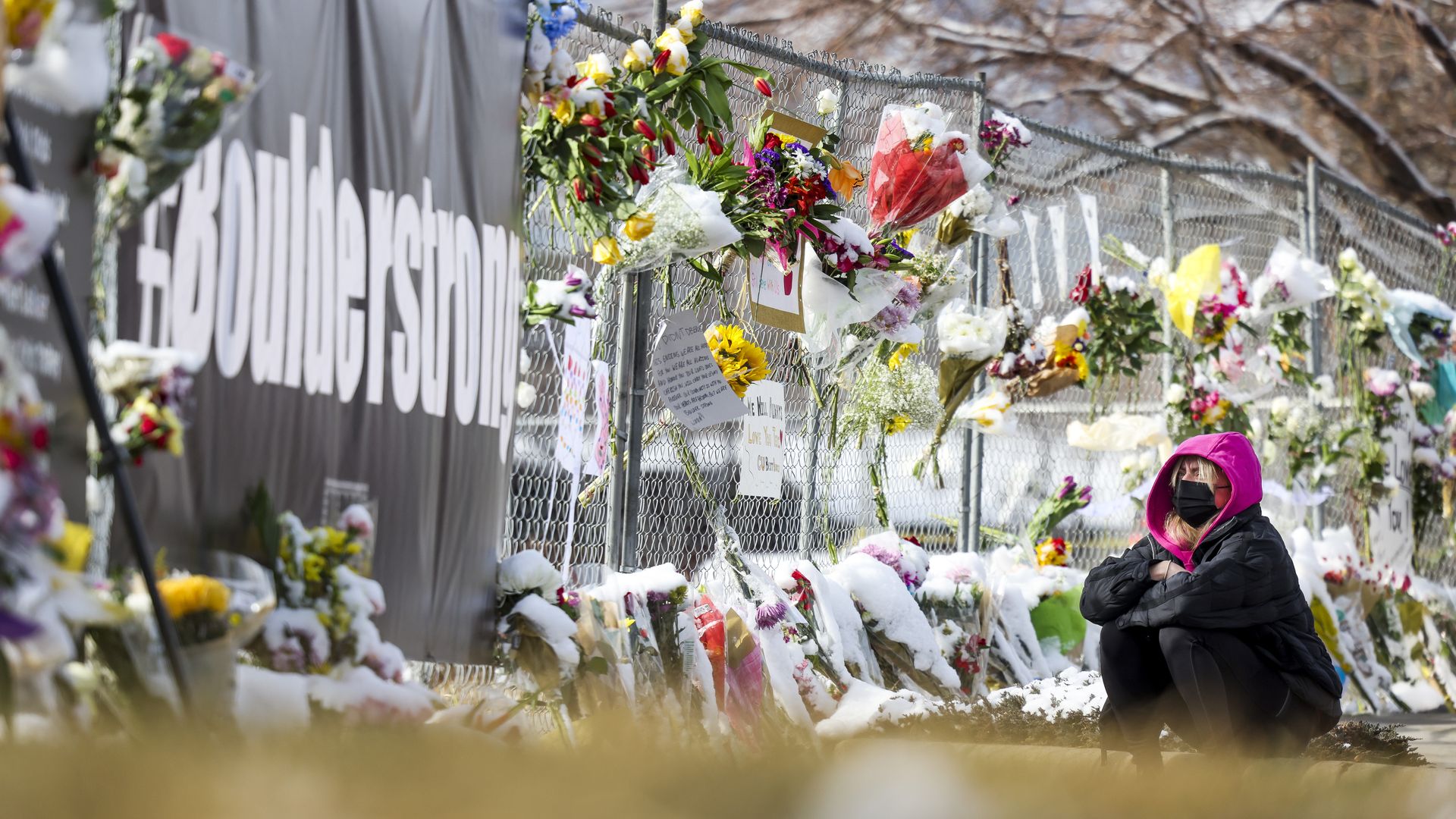 Gianna Giorlando sits next to a makeshift memorial for the victims of a mass shooting outside a King Soopers grocery store on March 24, 2021 