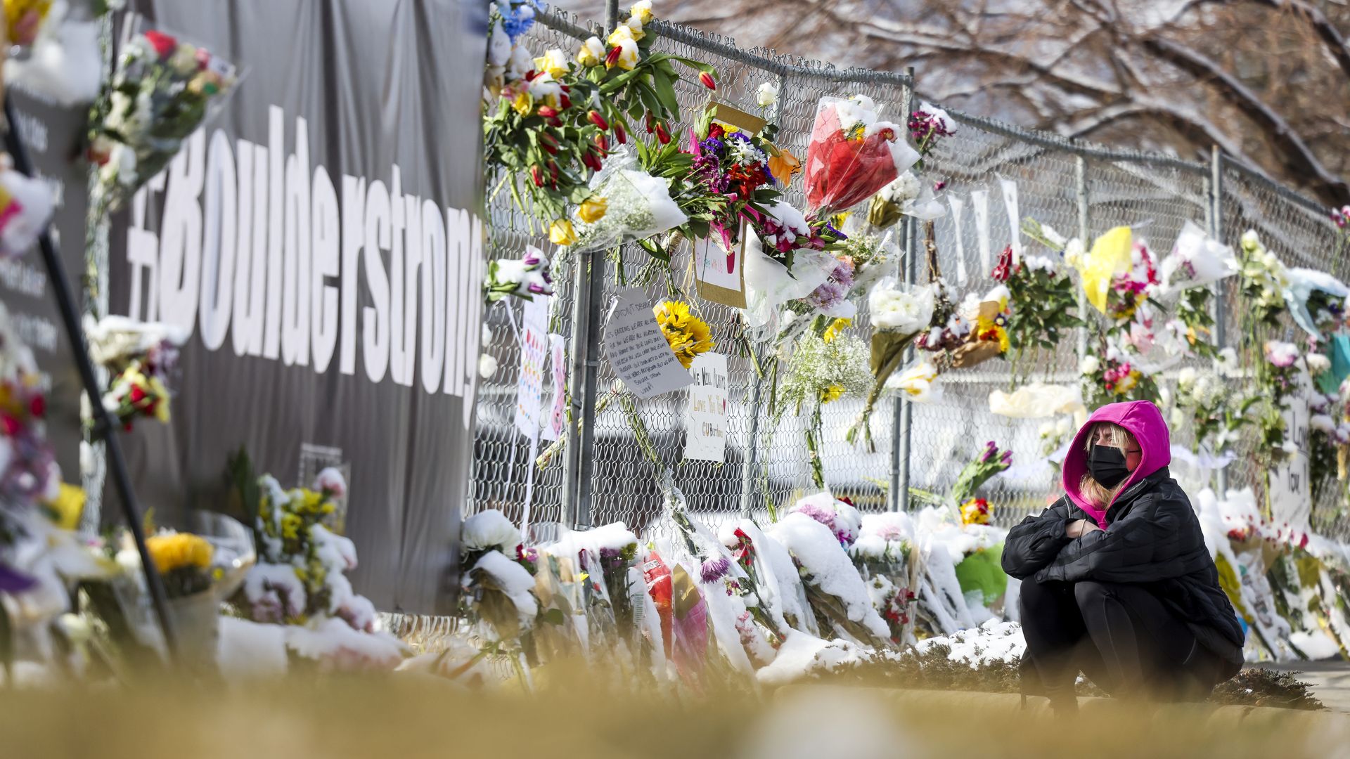 Gianna Giorlando sits next to a makeshift memorial for the victims of a mass shooting outside a King Soopers grocery store on March 24, 2021