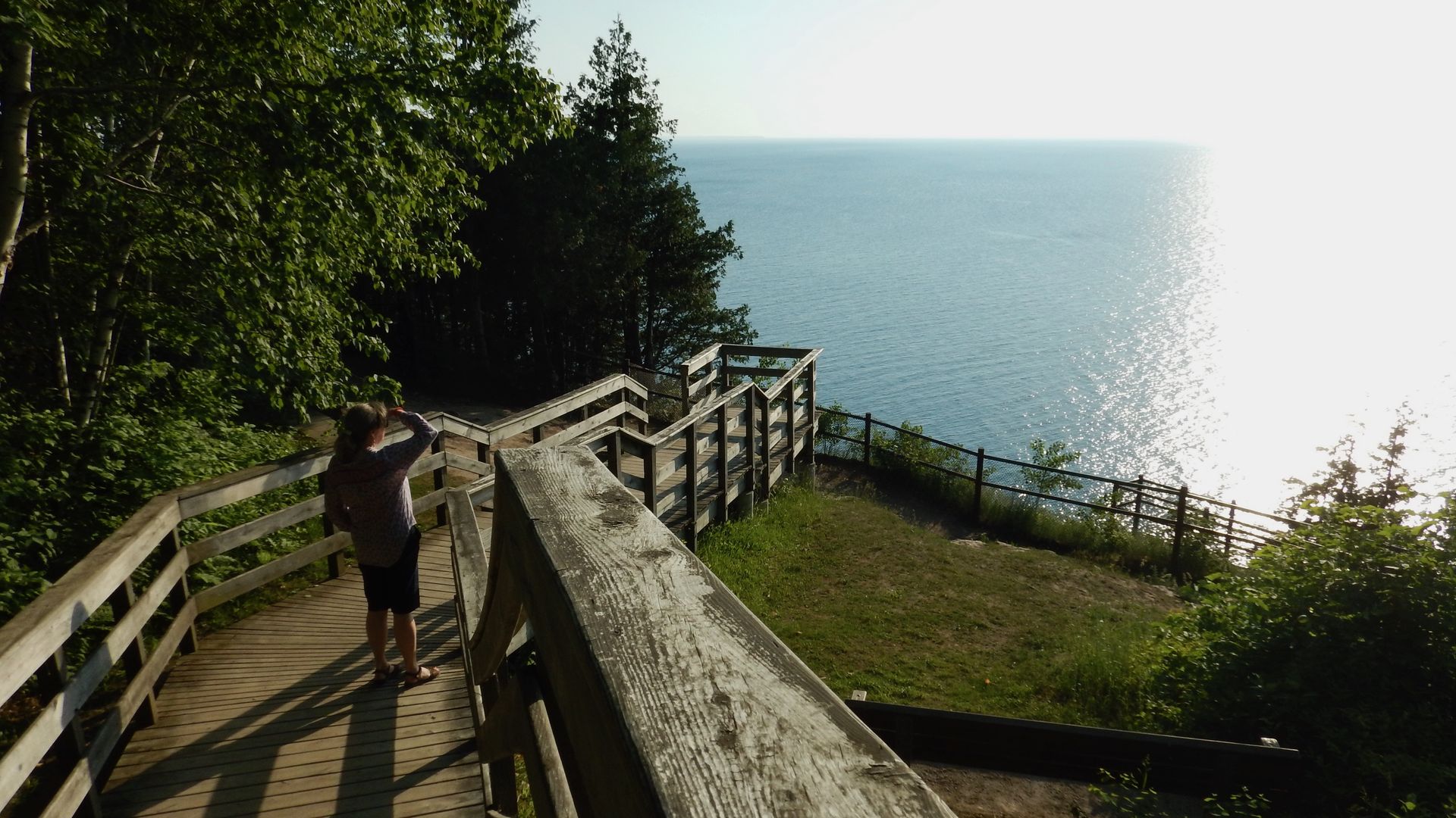 Photo of a woman walking on a deck looking at lake 